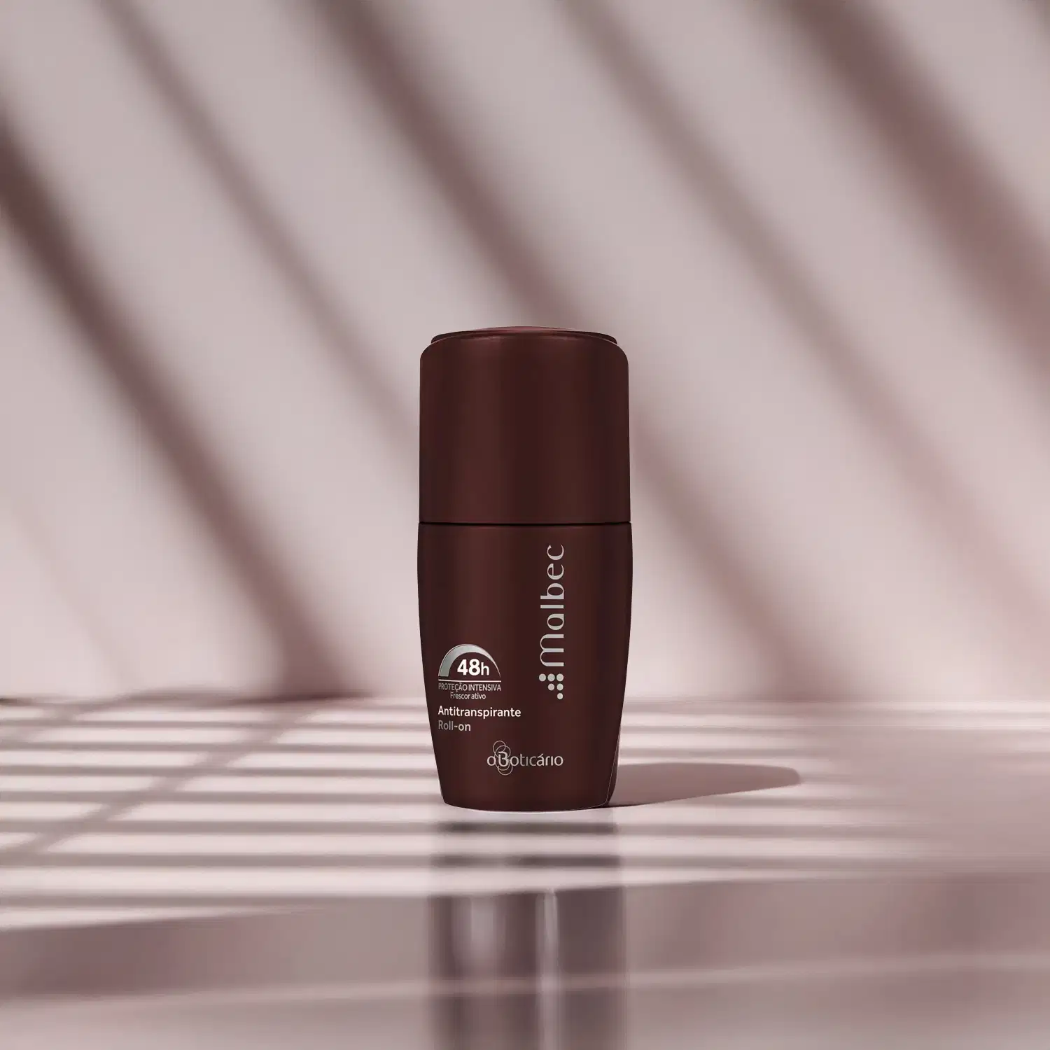 Imagem de embalagem de desodorante antitranspirante roll-on na cor vinho da marca Malbec sobre superfície clara com sombras suaves, em ambiente iluminado e minimalista.