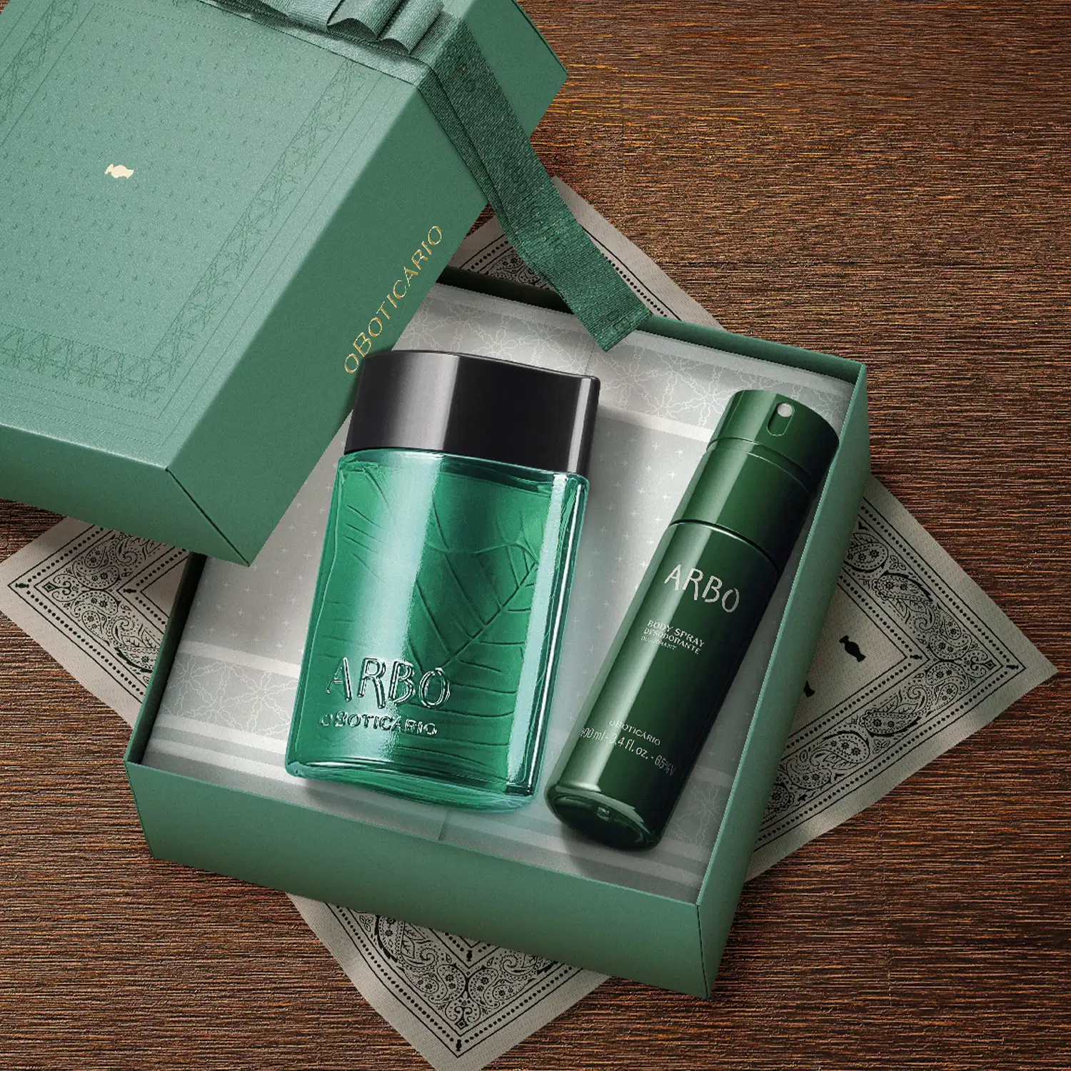 Imagem de caixa verde contendo um frasco de desodorante colônia Arbo e body spray da mesma marca, sobre superfície de madeira com detalhes decorativos.