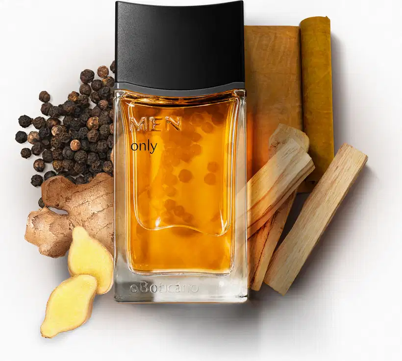 Imagem de um frasco de desodorante colônia da marca Men Only sobre superfície branca, rodeado por especiarias, raízes e pedaços de madeira, em cenário minimalista com cores quentes.