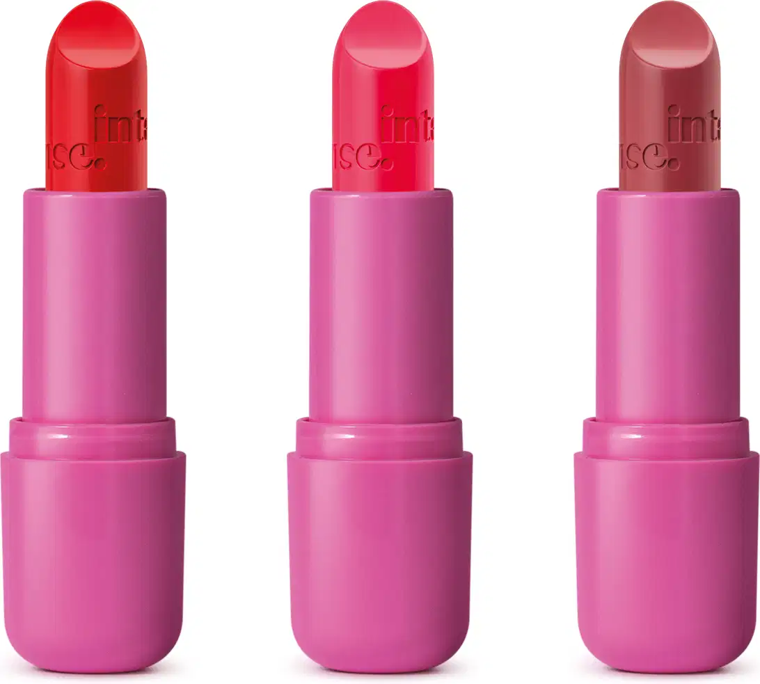 Três batons da marca Intense em embalagens pink. Eles estão abertos e é possível ver as balas de três cores diferentes, um vermelho, um pink e um rosa envelhecido, todos com a marca intense gravada em baixo relevo na bala.