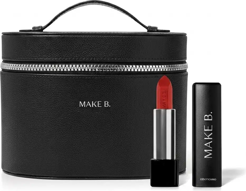 Frasqueira de maquiagem preta com zíper e alça, com aspecto rígido e estruturado feita em tecido tipo couro e logo Make B. em hot stamping prata e um batom vermelho vivo aberto com a bala visível, corpo prateado e base preta com tampa preta ao lado.
