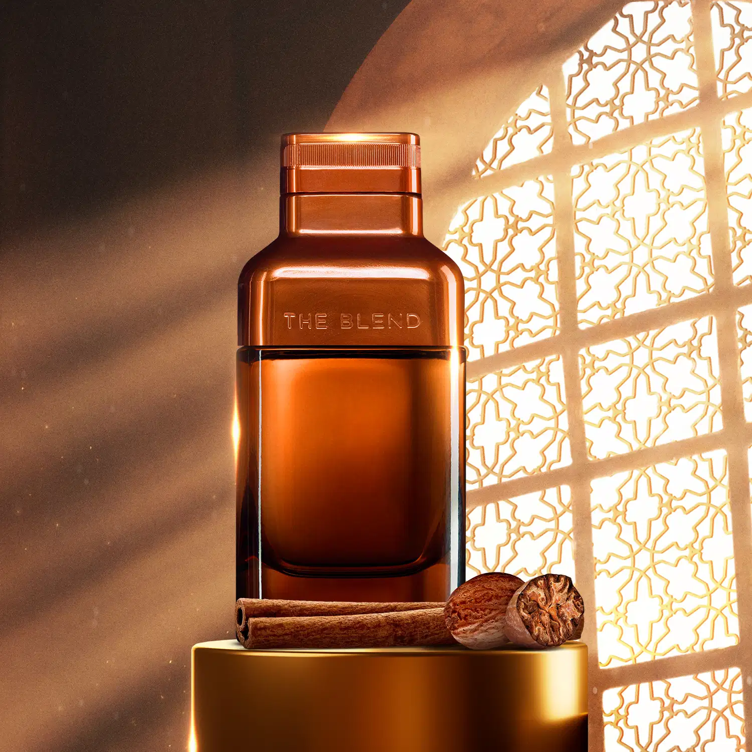Vidro em tom de marrom fosco com detalhes em marrom metalizado e letras azuis contendo Eau de Parfum The Blend posicionado em base dourada, com canela e noz-moscada ao lado, sob luz natural que atravessa painel geométrico dourado ao fundo.