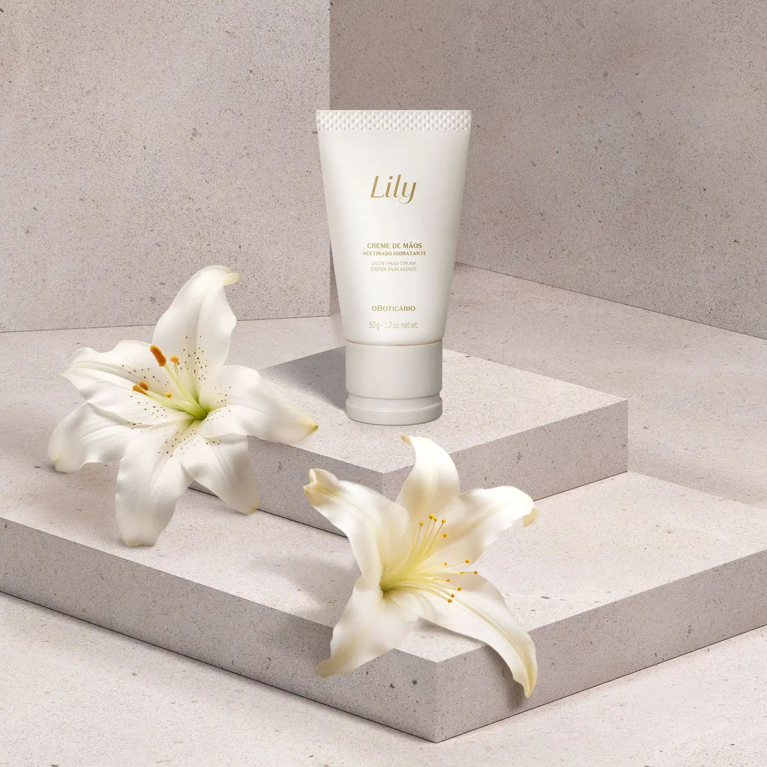 Uma biisnaga branca com tampa bege e letras marrons de creem de mãos acetinado hidratante da marca Lily está em uma plataforma branca, com flores brancas ao redor, em um cenário em tons de cinza.
