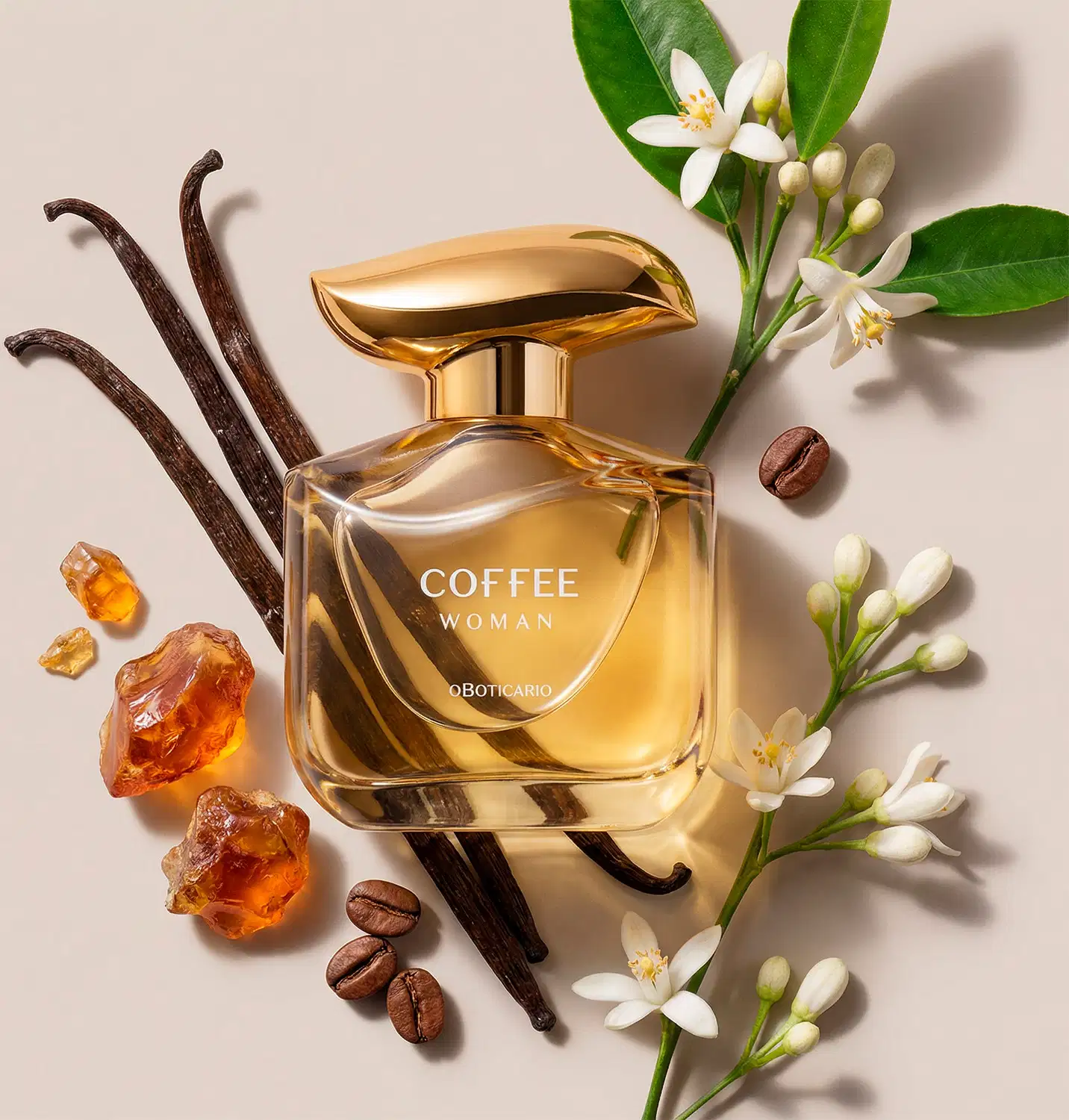 Imagem de um frasco dourado com tampa da mesma tonalidade do desodorante colônia Coffee Woman Floriental Ambarado sobre superfície bege, com flores brancas, grãos de café e pedras âmbar ao redor, em ambiente com tons neutros.