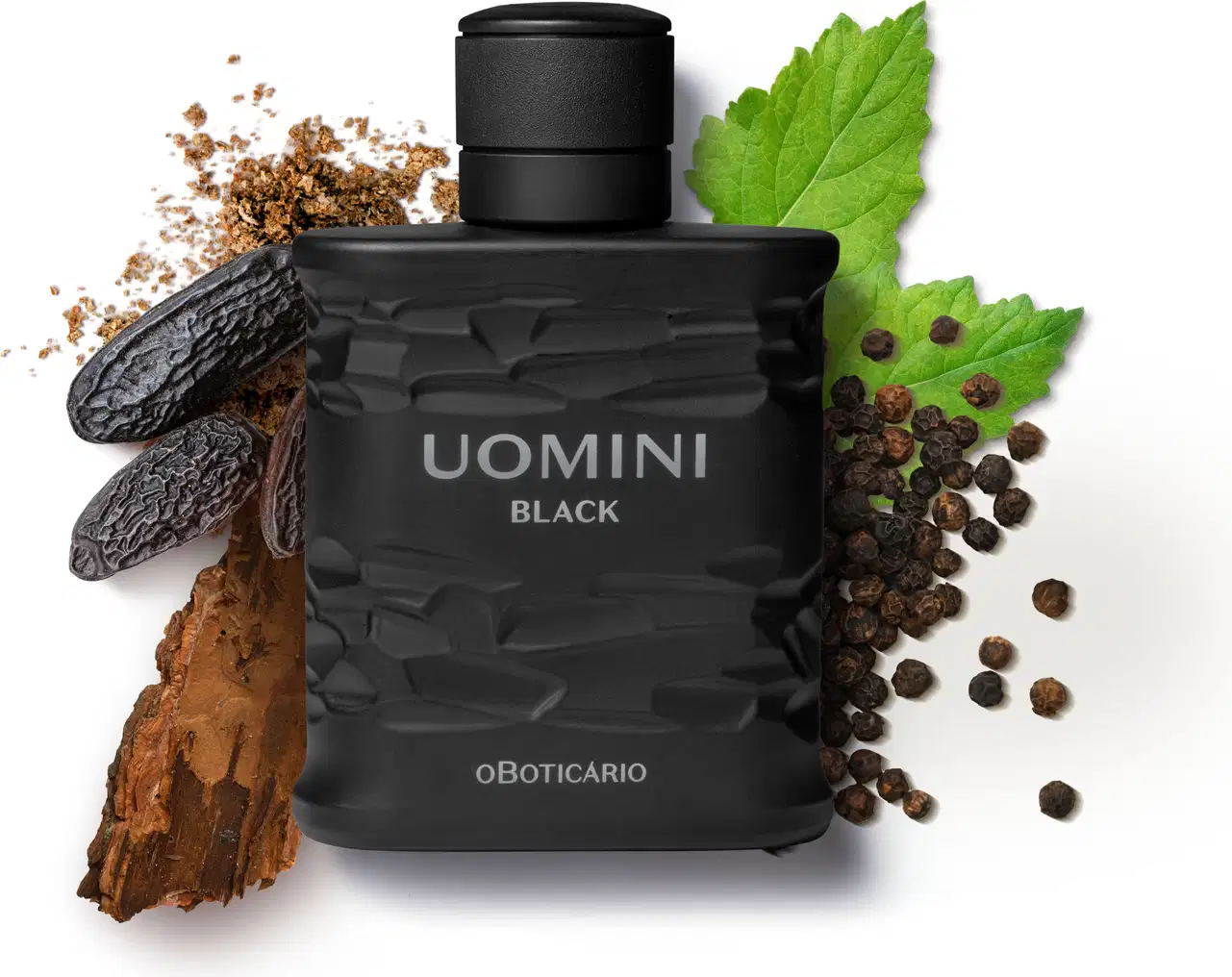 Frasco retangular preto com texturas onduladas, tampa preta e letras cinzas, contendo desodorante colônia da marca Uomini Black, rodeado por folhas verdes, grãos de pimenta, pedaços de madeira e fava de tonka.