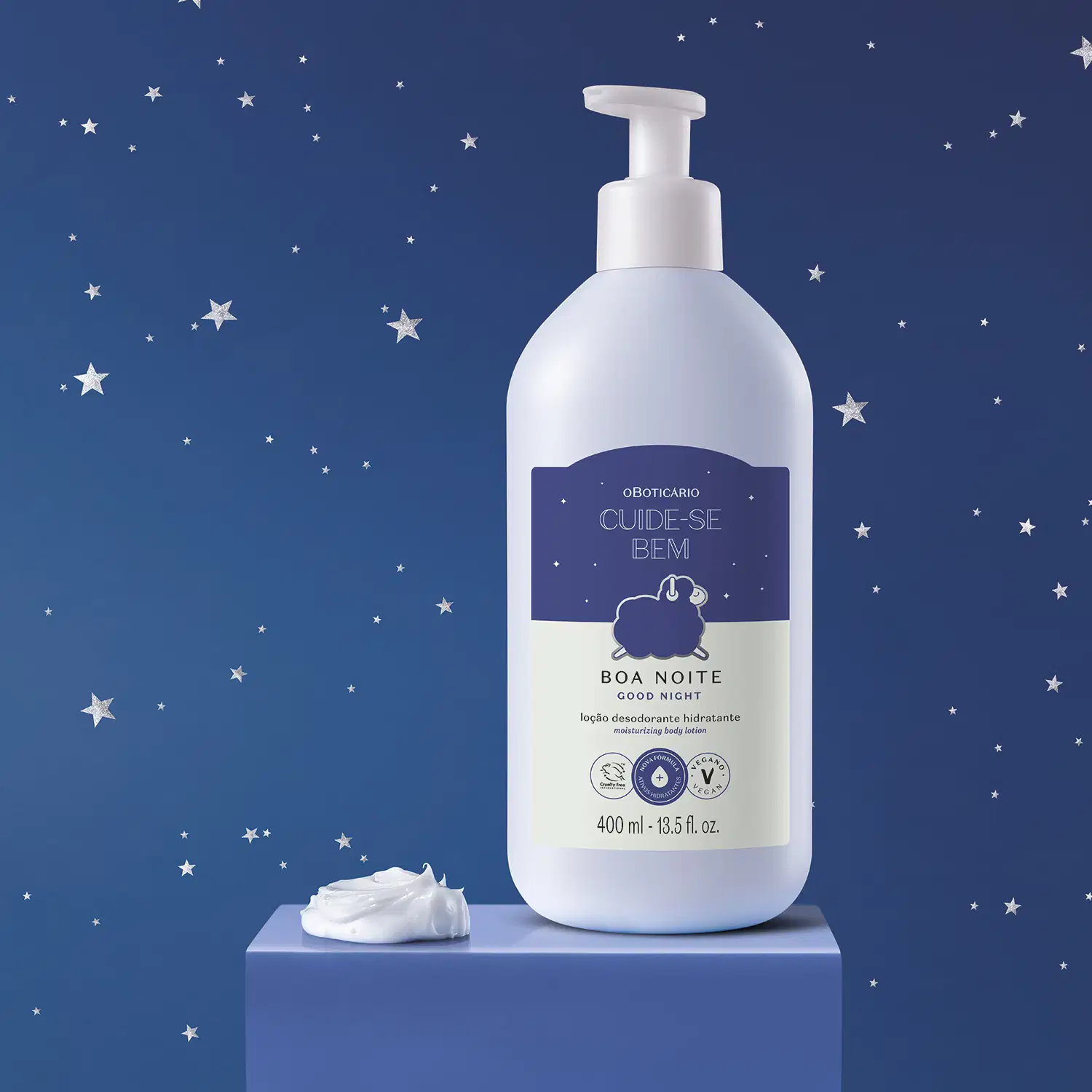 Frasco branco com bomba dosadora e rótulo azul escuro e branco com ovelhinha ilustrada contendo 400ml de loção hidratante corporal Cuide-se Bem Boa Noite em superfície azul escuro, fundo azul escuro com estrelas brancas e uma porção do produto ao lado.