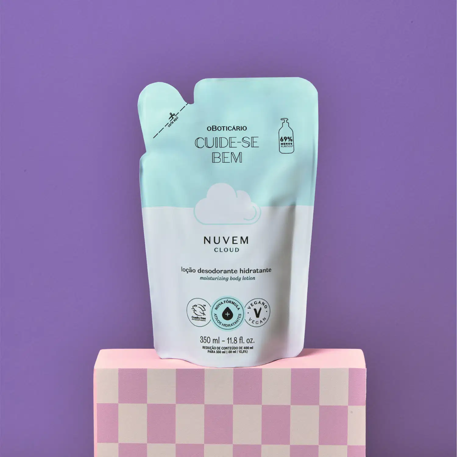 Refil de loção hidratante corporal Cuide-se Bem Nuvem em sachê nas cores azul e branco com nuvem ilustrada em fundo roxo, apoiada sobre superfície rosa com padrão quadriculado.