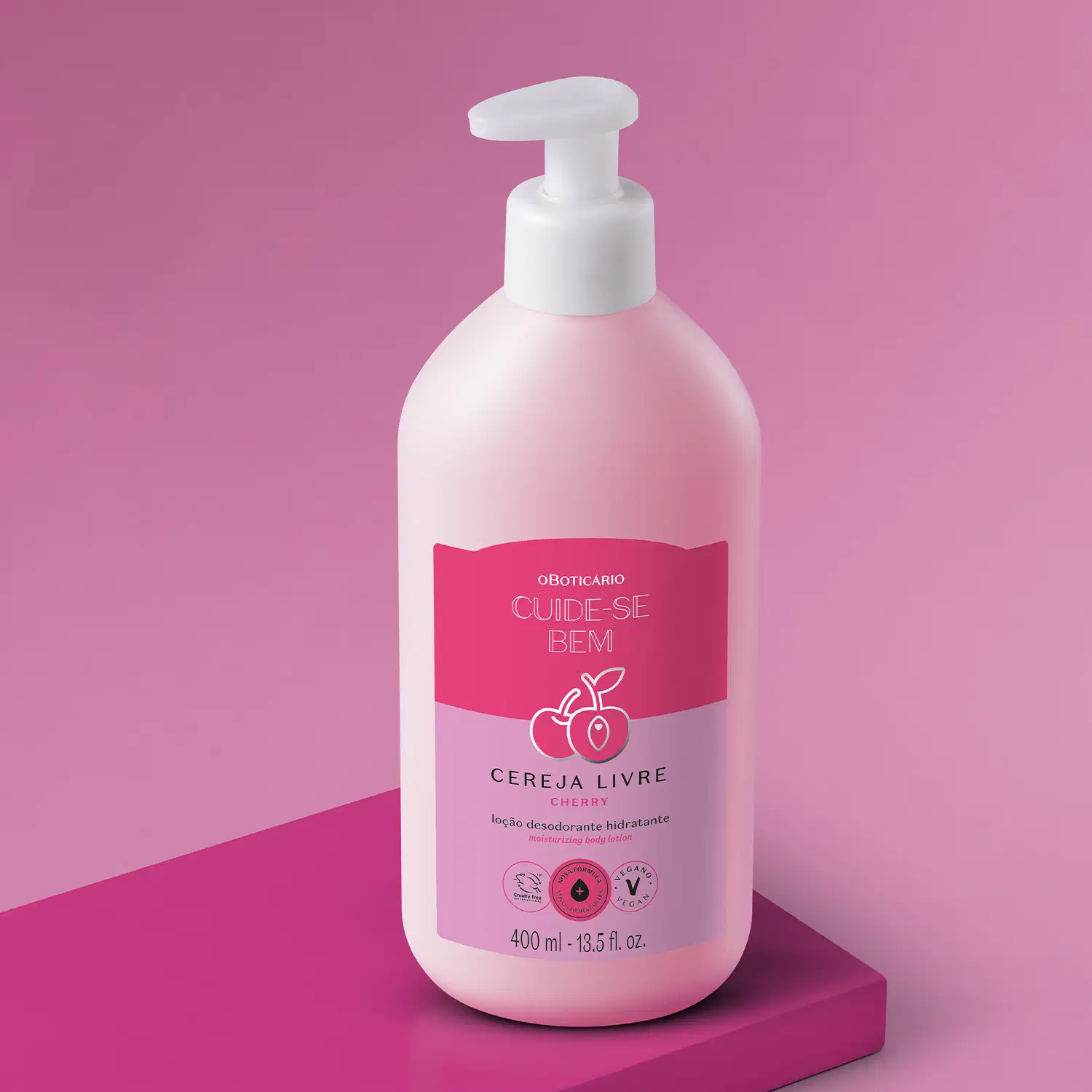 Frasco branco com bomba dosadora e rótulo nas cores rosa e lilás com cerejas ilustradas contendo loção hidratante corporal Cuide-se Bem Cereja Livre. A embalagem está em fundo lilás sobre plataforma rosa.