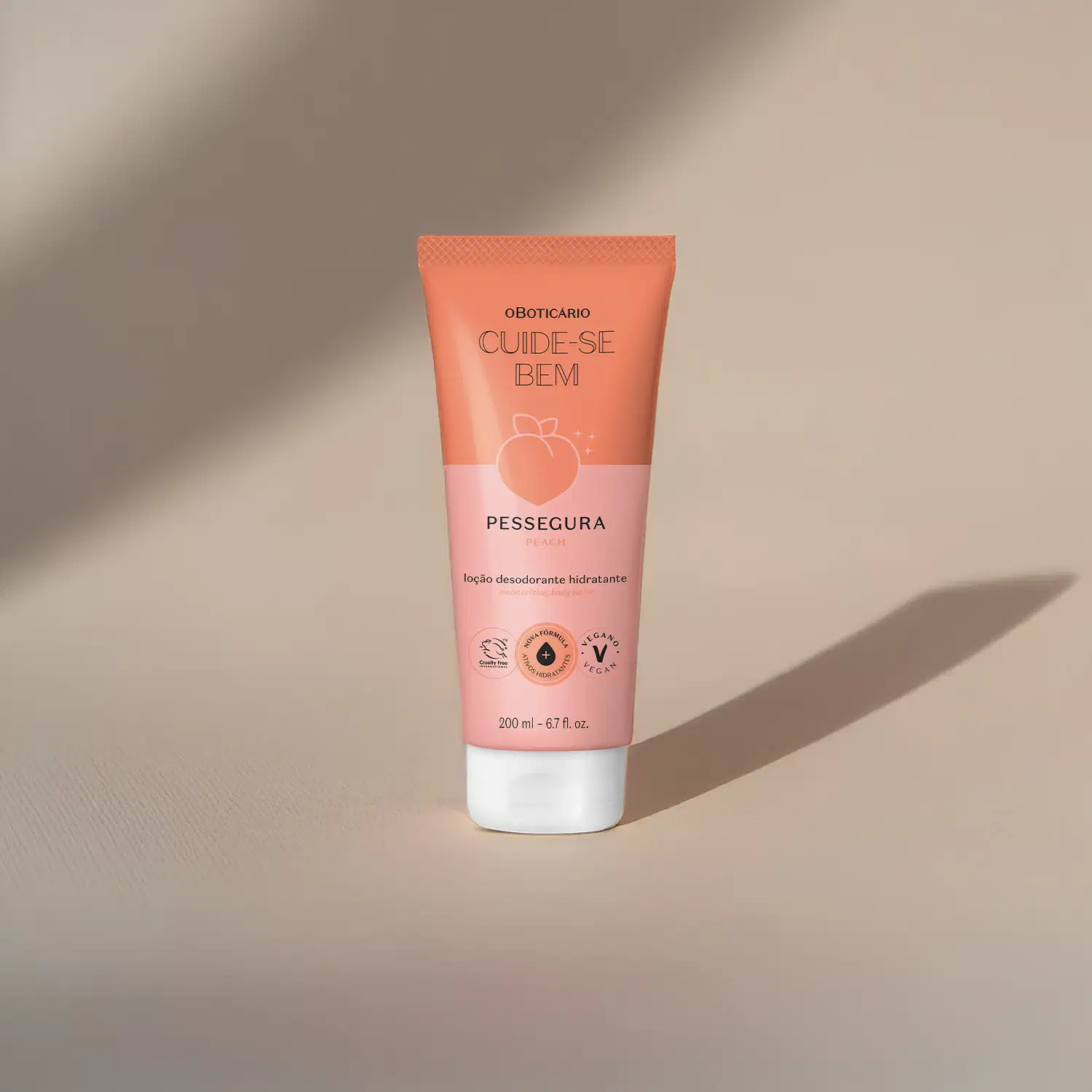 Bisnaga em tons de rosa com tampa transparente, letras pretas e pêssego ilustrado contendo 200ml de loção hidratante corporal da marca Cuide-se Bem Pessegura em fundo bege com sombras.