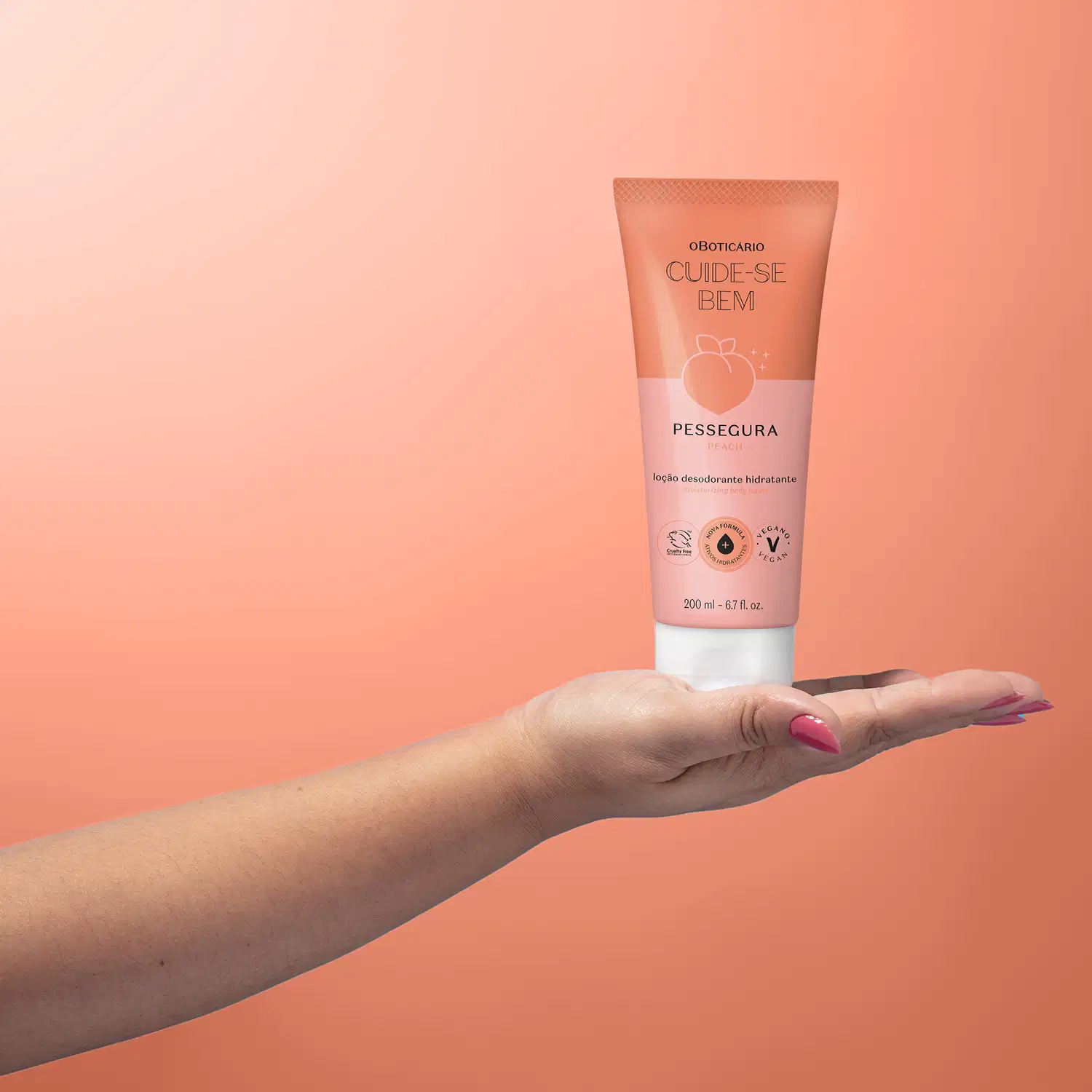 Mão feminina segurando um frasco rosa e branco com pêssego ilustrado e tampa branca de loção hidratante corporal Cuide-se Bem Pessegura.