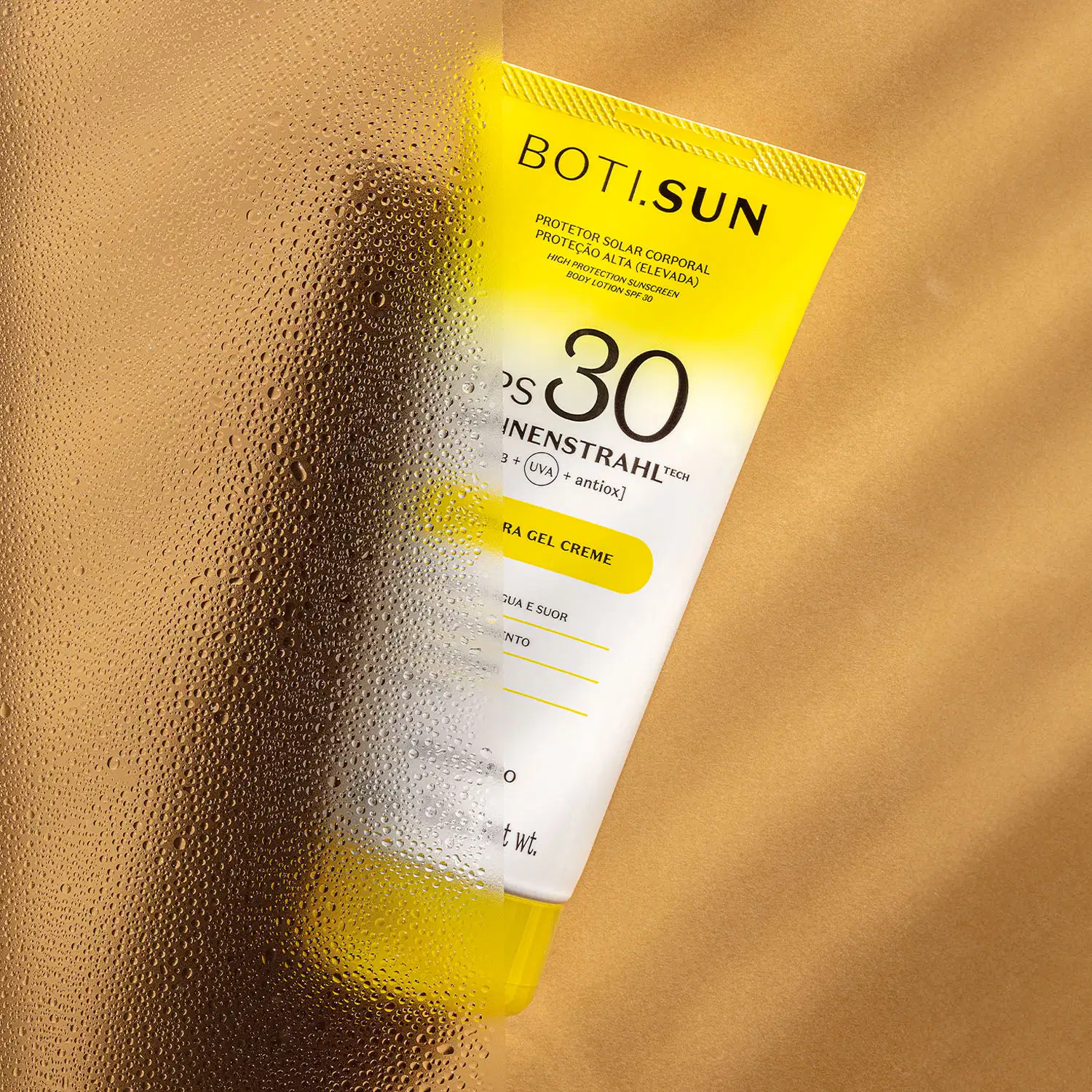 Bisnaga amarela e branca com tampa amarela e letras pretas contendo 200g de protetor solar corporal FPS 30 da marca Boti.Sun em um fundo bege com sombras onduladas.
