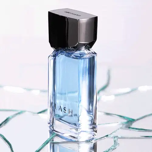 Vídeo mostra frasco de item de perfumaria da marca Clash fazendo um giro de 360 graus sobre superfície de vidro craquelada, com reflexos e iluminação azulada, em ambiente minimalista e claro.
