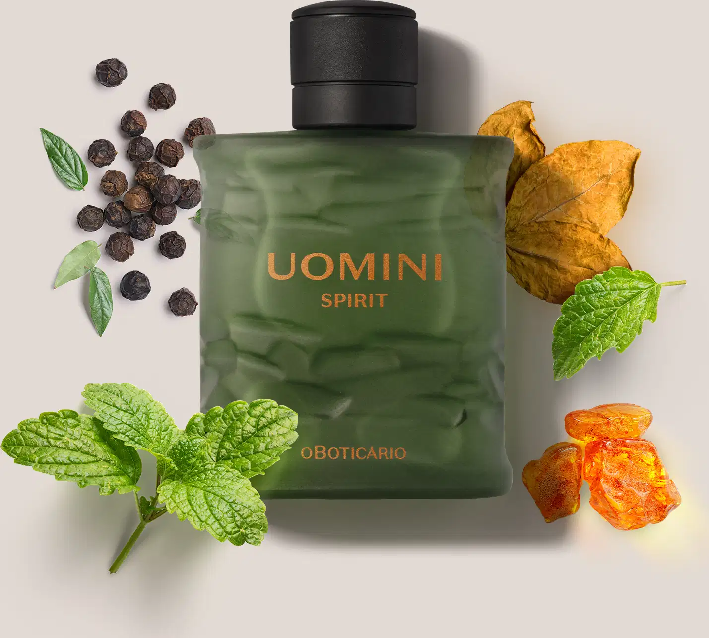 Frasco retangular em tom de verde oliva com tampa texturizada preta e letras laranjas de desodorante colônia Uomini Spirit., cercado por folhas verdes, pimenta-do-reino preta e laranja desidratada sobre superfície clara.