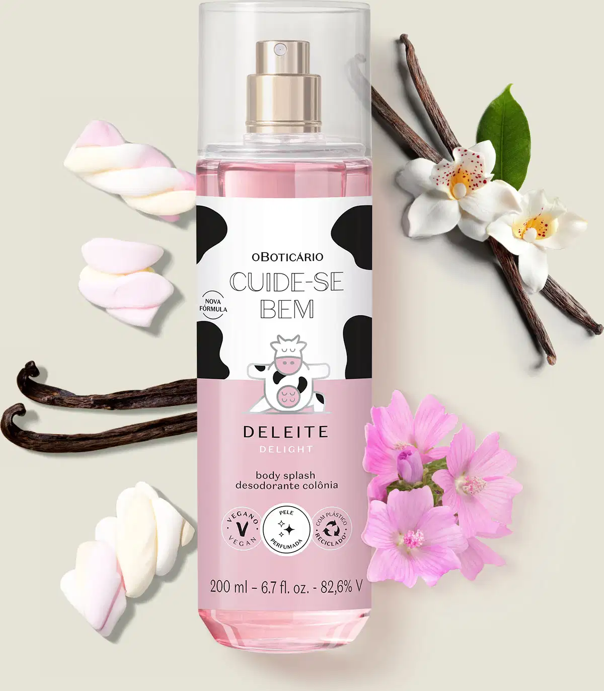 Frasco com líquido rosa, pulverizador prateado e rótulo branco e rosa com ilustração de vaca contendo 200ml de body splash Cuide-se Bem Deleite  rodeada por flores brancas, bastões de baunilha e marshmallows coloridos sobre superfície clara.
