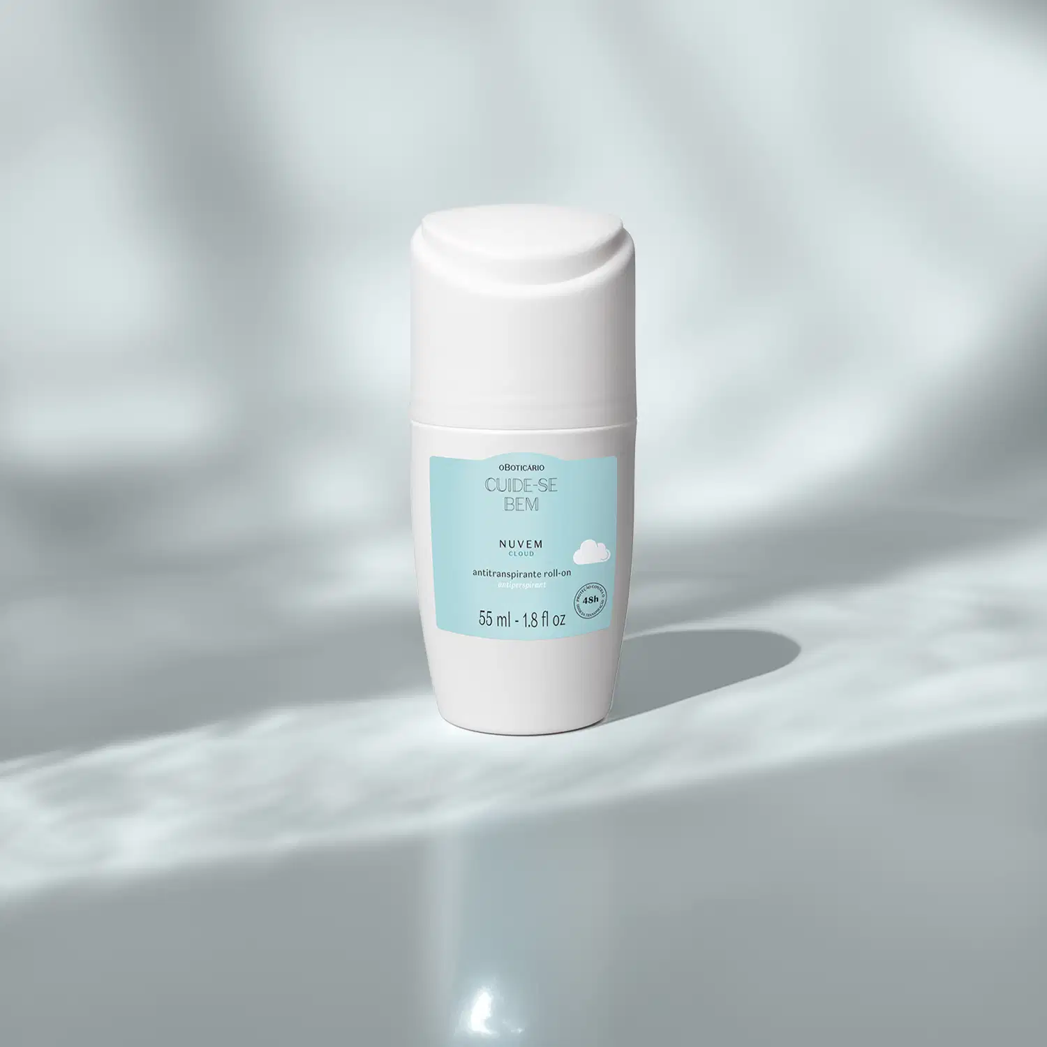 Frasco branco com rótulo azul claro e nuvens ilustradas contendo 55ml de antitranspirante roll-on Cuide-se Bem Nuvem em cenário claro com sombras.
