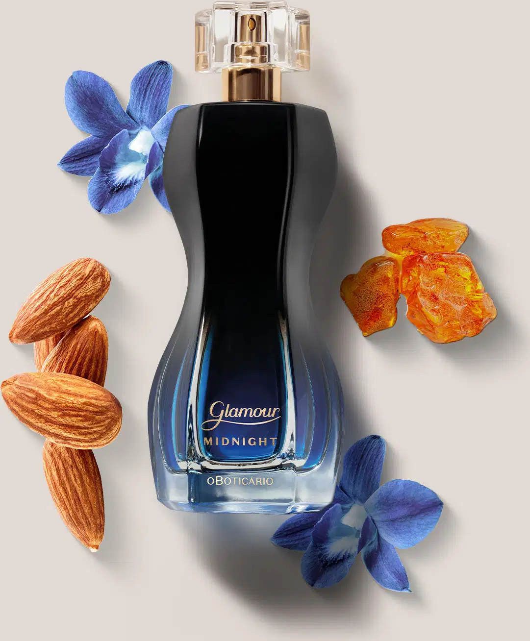 Vidro preto e azul de desodorante colônia Glamour Midnight rodeado por flores azuis, frutas secas alaranjadas e amêndoas sobre fundo bege. O cenário sugere um ambiente de luxo e sofisticação.