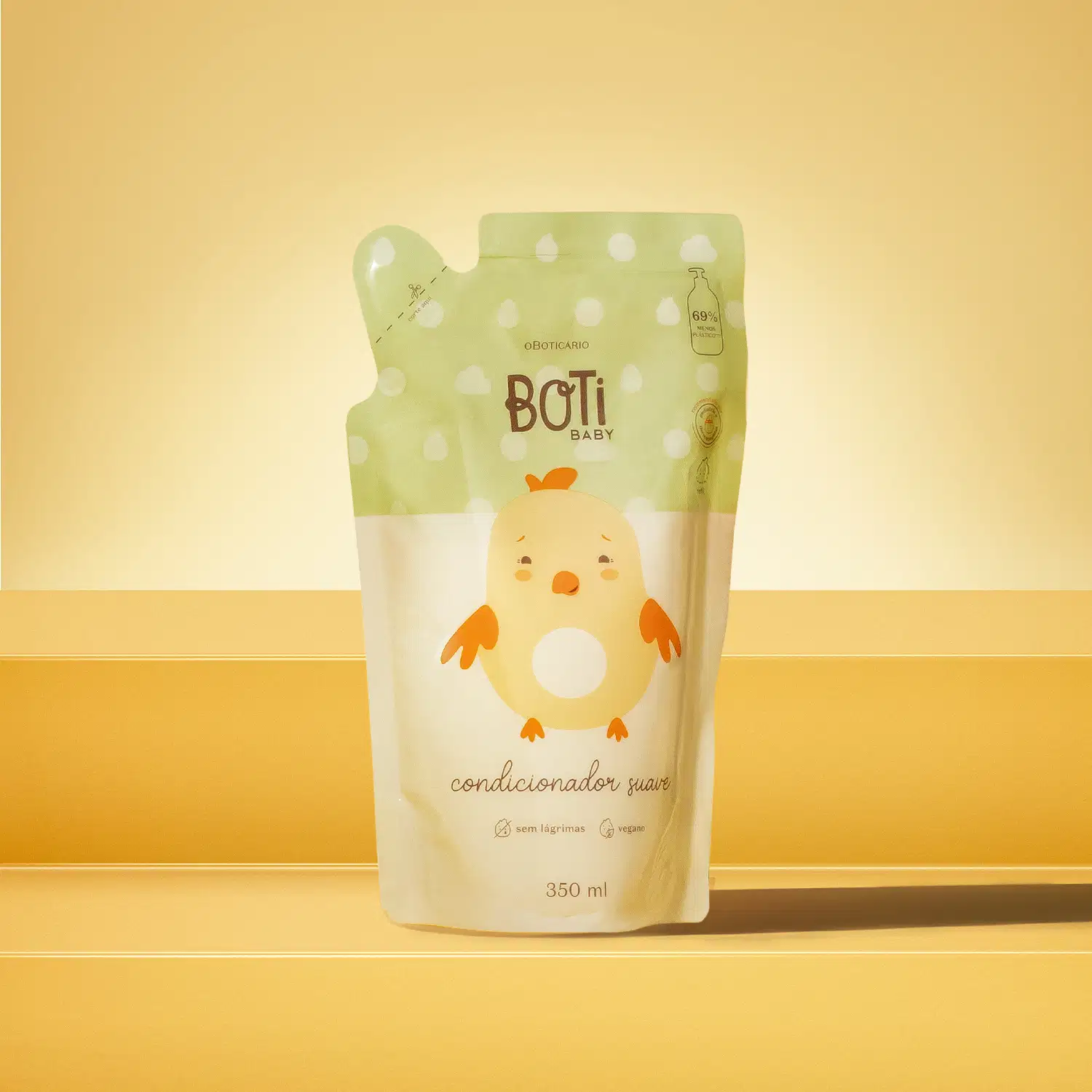Refil de condicionador suave da marca Boti Baby em forma de sachê nas cores rosa e amarelo claro com ilustração de passarinho amarelo com detalhes laranjas. O fundo e superfície são em tons de laranja.
