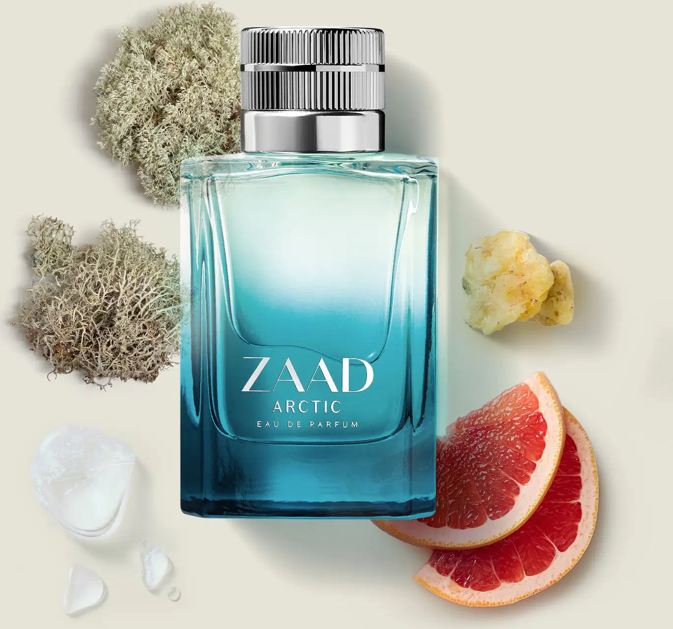 Vidro retangular com degradê de transparente e azul, tampa cinza e letras brancas contendo Eau de Parfum Zaad Arctic, rodeado por fatias de frutas frescas, musgos, minerais brutos e pedra de gelo.