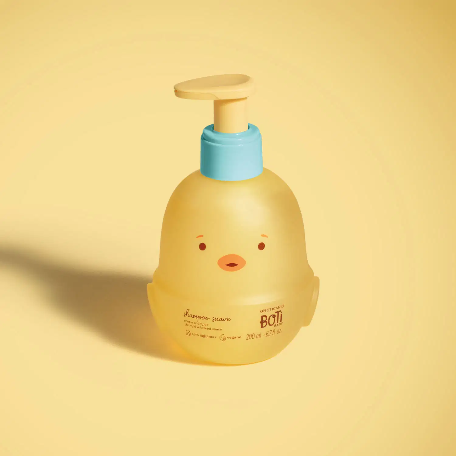 Frasco em forma de passarinho amarelo com detalhes laranjas, tampa azul e bomba dosadora amarela de shampoo suave da marca Boti Baby em fundo alaranjado.