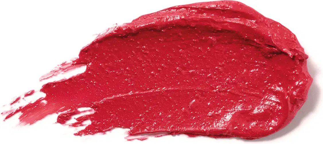Textura cremosa e brilhante do batom glossy na cor Vermelho Raspyberry da marca Make B. A aparência é brilhante e leve e está espalhada em superfície branca.