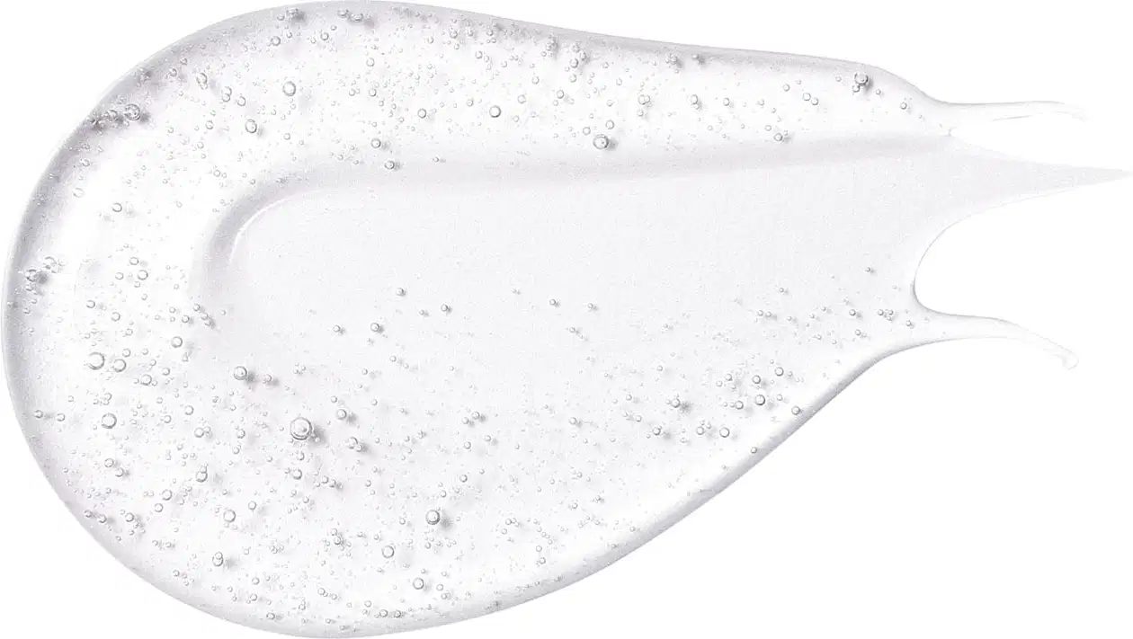 Textura gelatinosa e transparente do gloss labial incolor da marca Intense com pequenas bolhas no produto, aplicada em superfície branca e lisa.