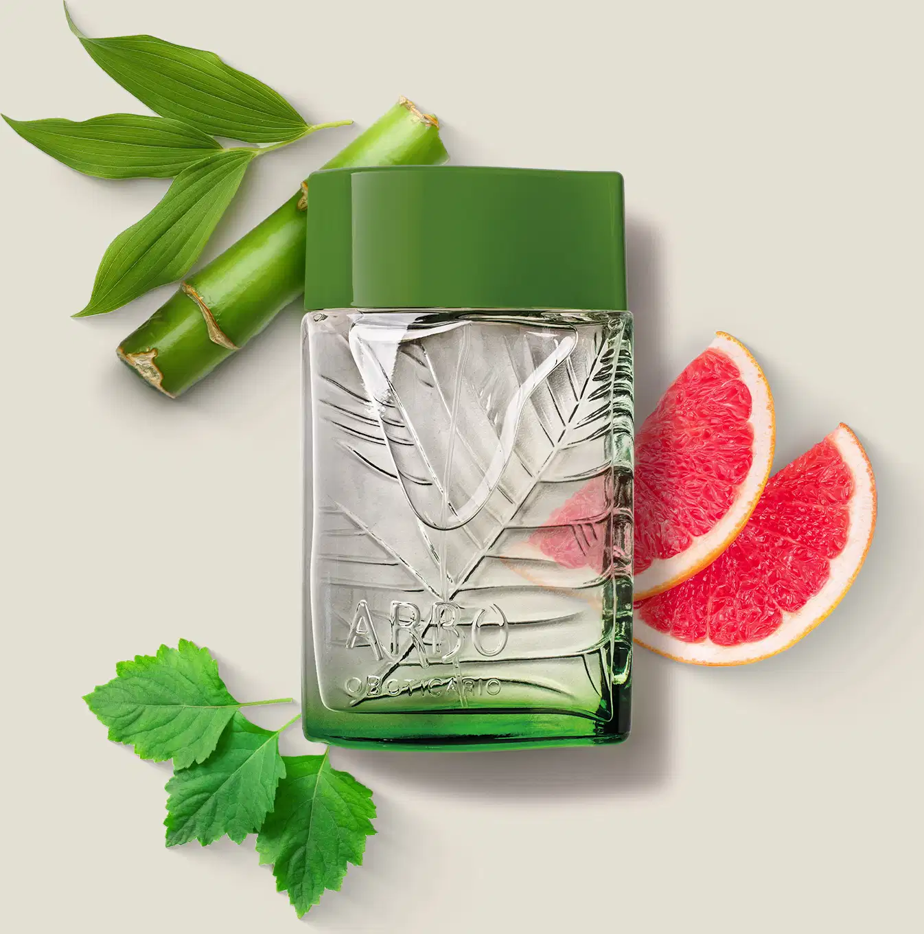 frasco verde transparente com líquido claro, folhagens em relevo e tampa verde escuro contendo desodorante colônia Arbo Puro com folhas verdes e fatias de toranja rosa ao redor, sobre superfície clara.