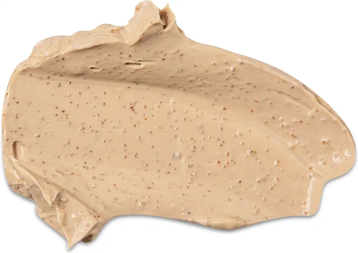 Textura cremosa e opaca do creme esfoliante corporal  Nativa Spa Ameixa Dourada com aparência densa e coloração amarelada espalhada em superfície branca.