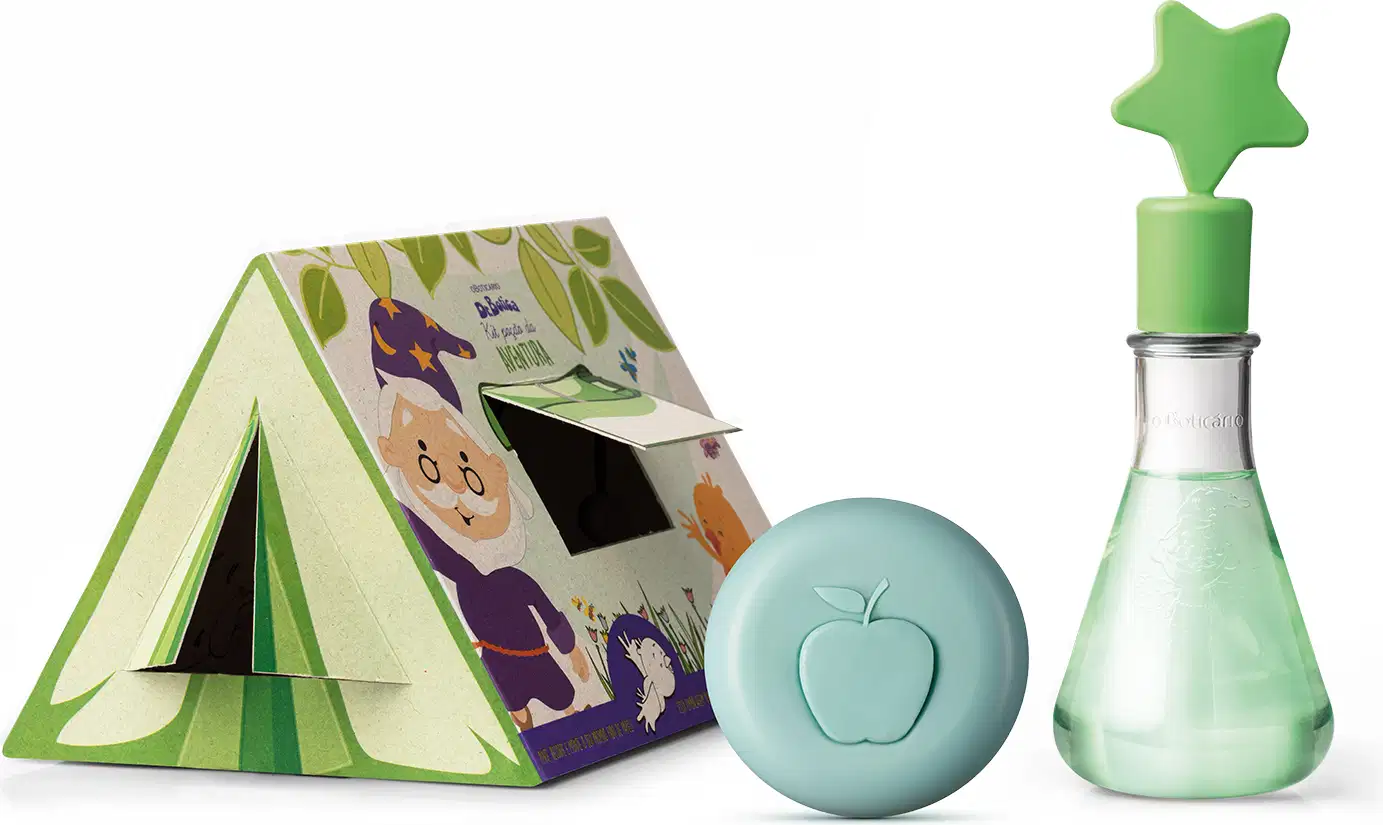 Caixa de papelão em formato de barraca de camping, sabonete em barra azul em formato redondo com uma maçã ilustrada e vidro de perfumaria infantil em formato de tubo laboratorial e estrela verde na ponta Poção de Aventura Dr. Botica.