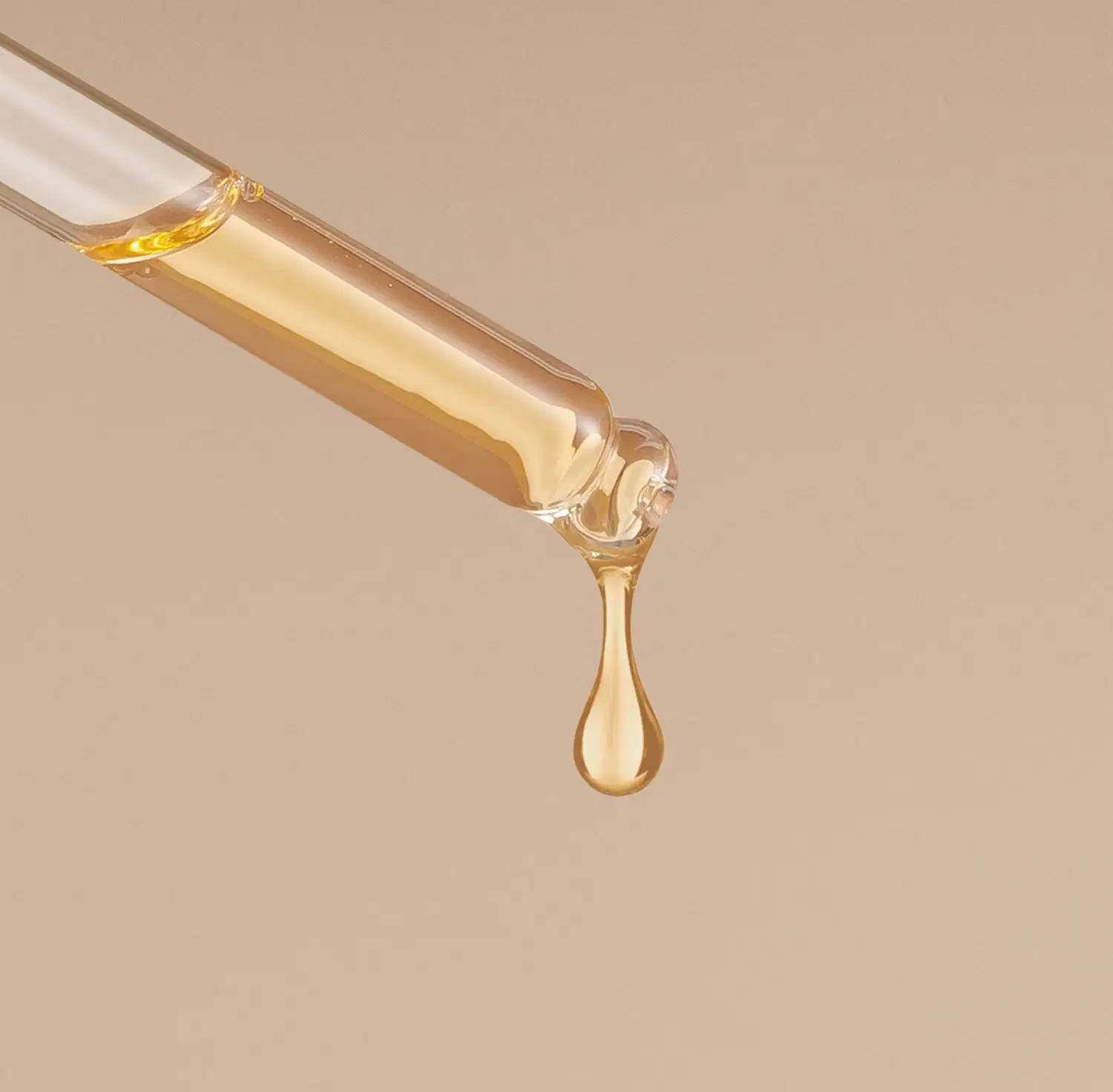 Um conta-gotas branco pinga uma gota de líquido dourado em um fundo bege.