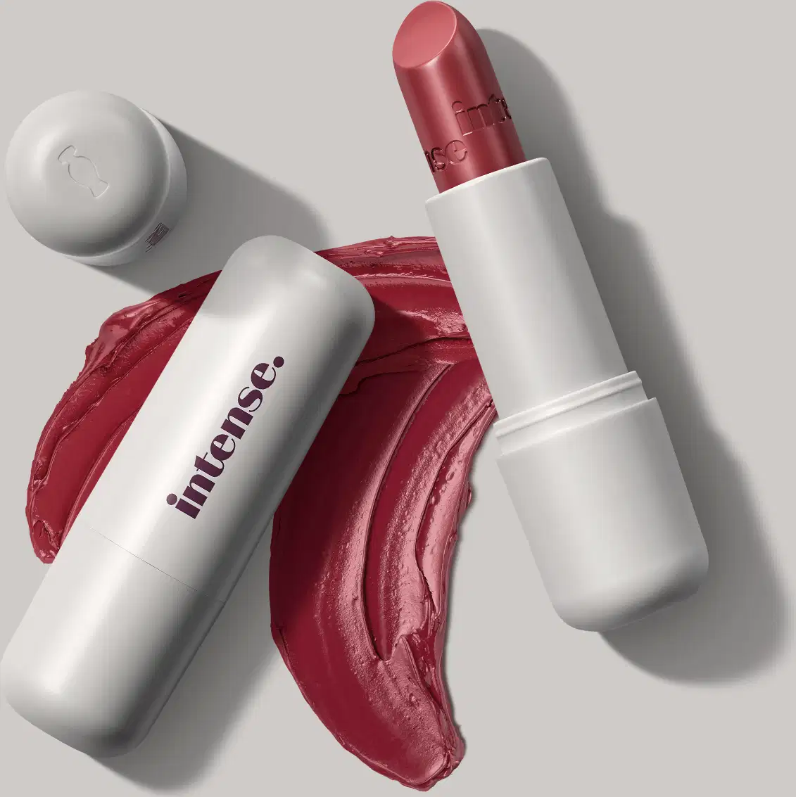 Batom cremoso na cor vermelho 350 da marca Intense, em embalagem toda branca com letras pretas na tampa, com uma quantidade de produto espalhada no fundo cinza.