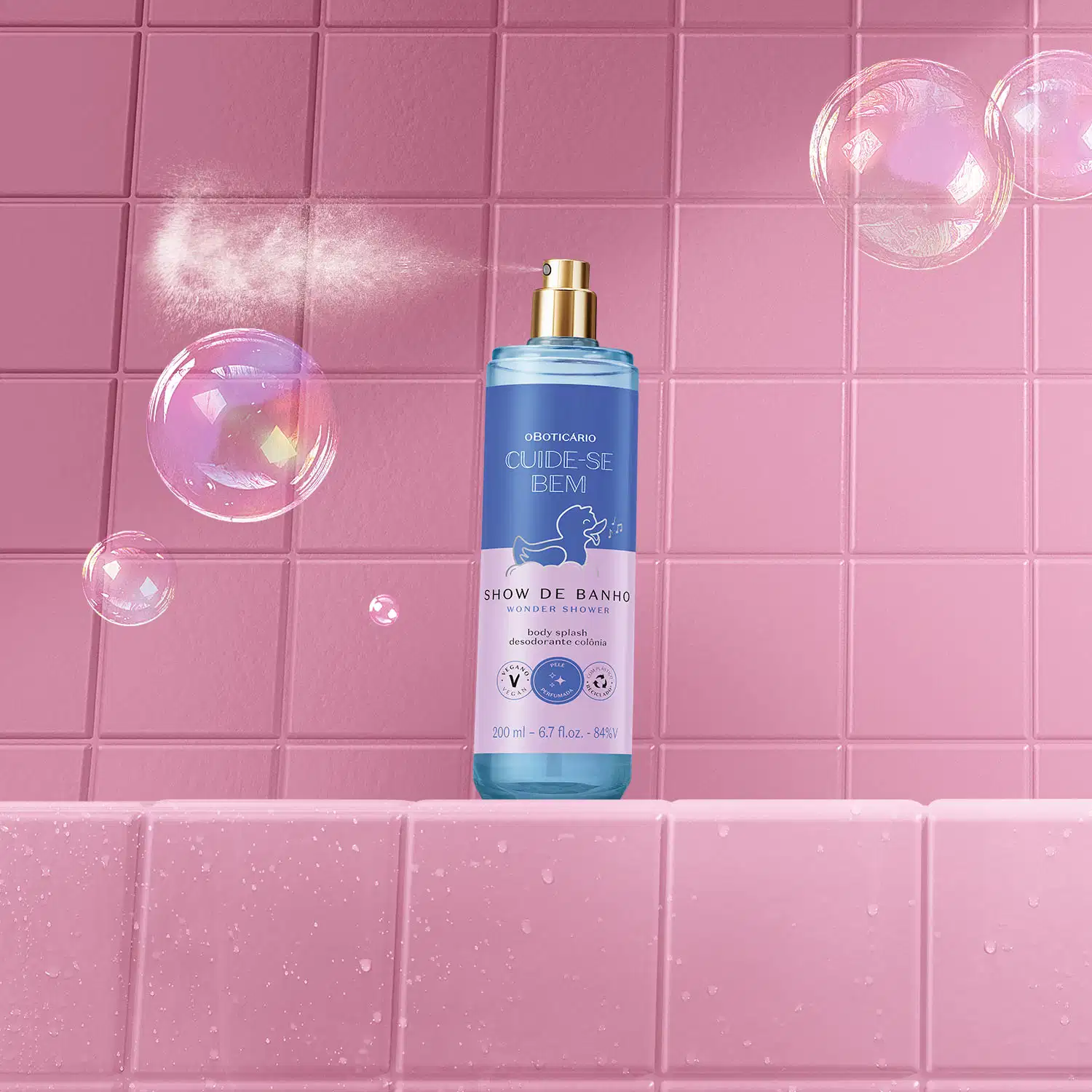 Frasco com líquido azul, pulverizador prateado, tampa transparente e rótulo azul e lilás com patinho de banho ilustrado  de body splash da marca  Cuide-se Bem Show de Banho. em ambiente rosa com bolhas de sabão flutuando ao redor.