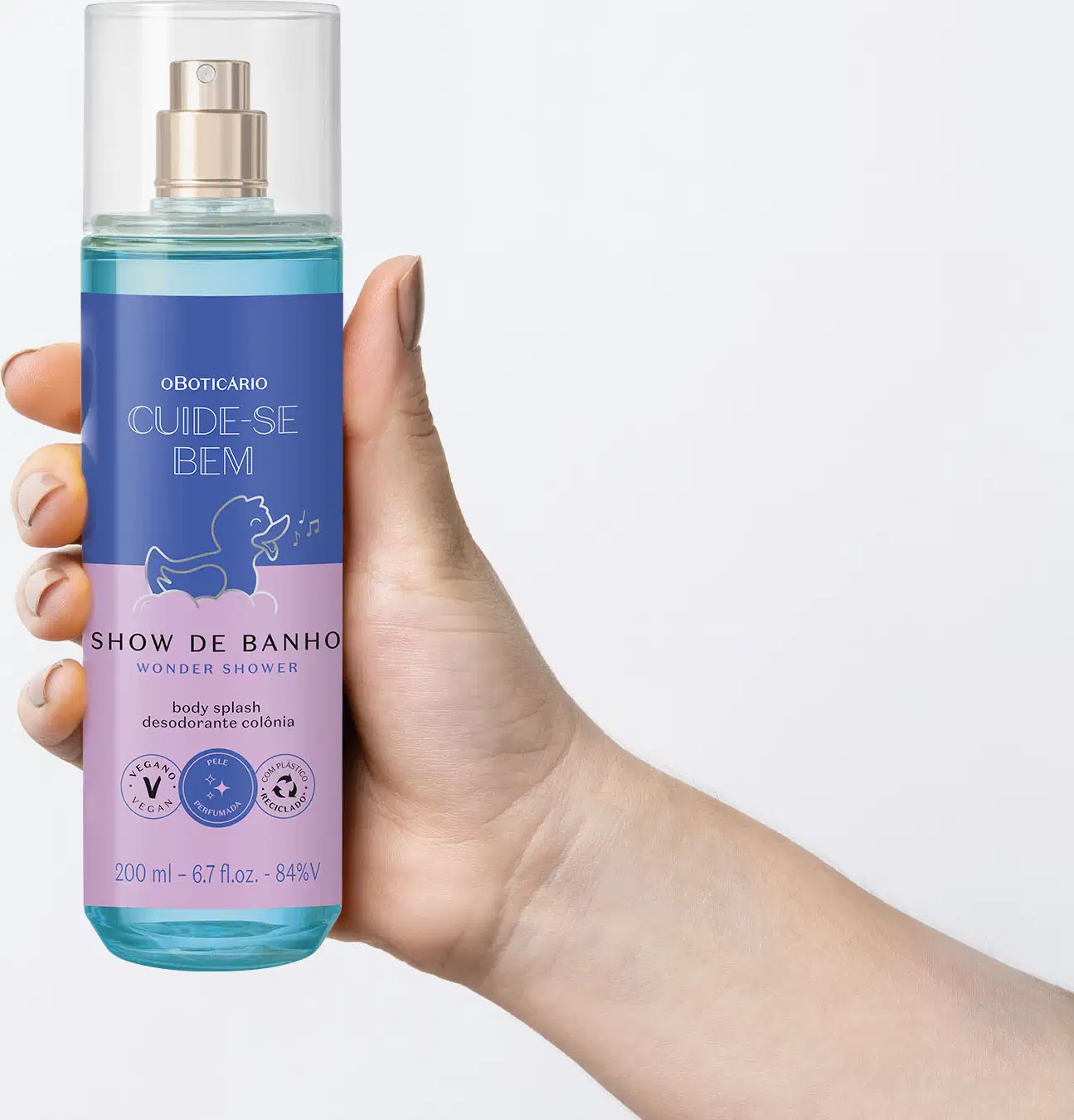 Mão segurando um Frasco com líquido azul, pulverizador prateado, tampa transparente e rótulo azul e lilás com patinho de banho ilustrado de body splash da marca  Cuide-se Bem Show de Banho em fundo azul claro.