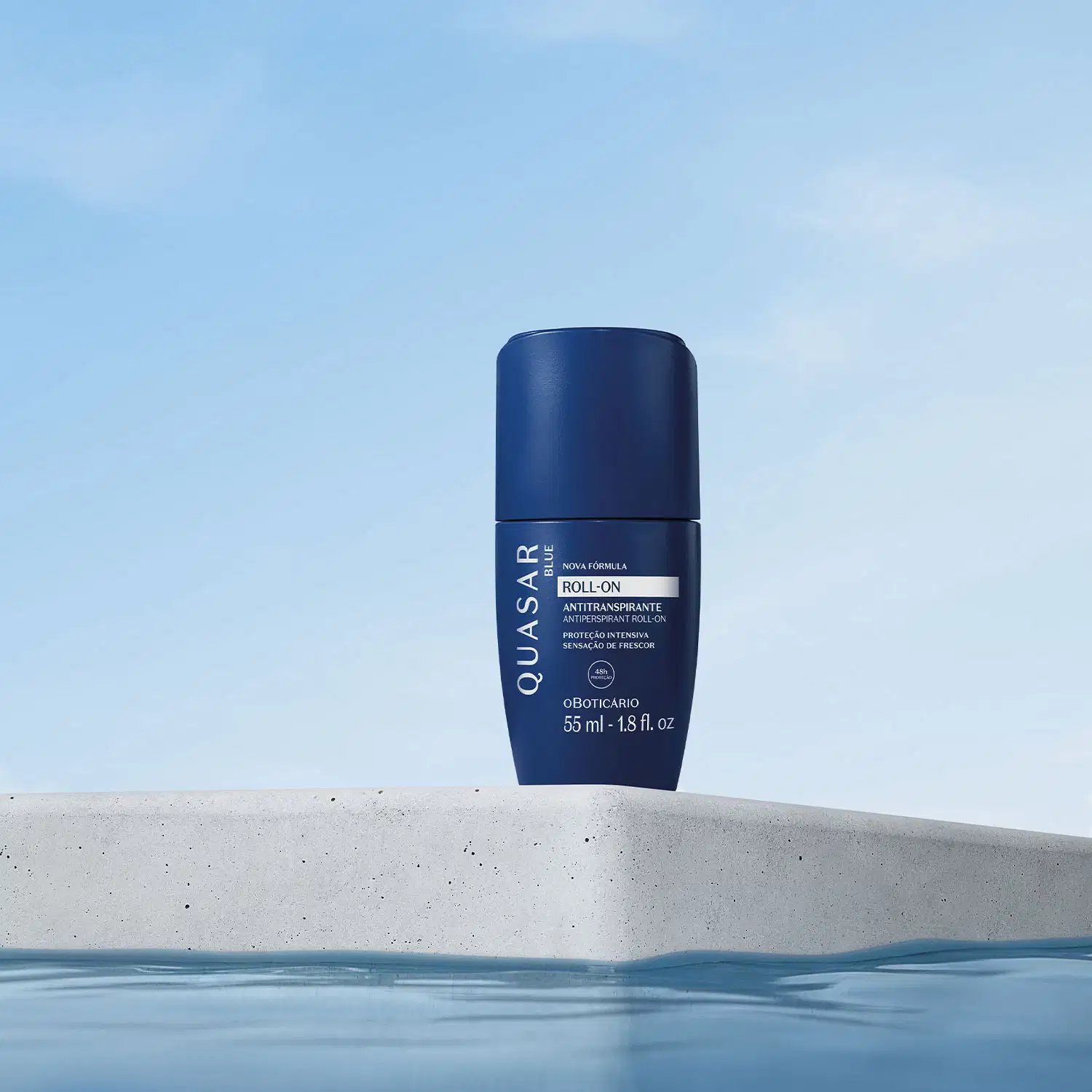 Frasco azul marinho com letras brancas contendo 55ml de antitranspirante desodorante roll-on da marca Quasar Blue flutuando sobre uma superfície de concreto cinza, com céu azul claro ao fundo.