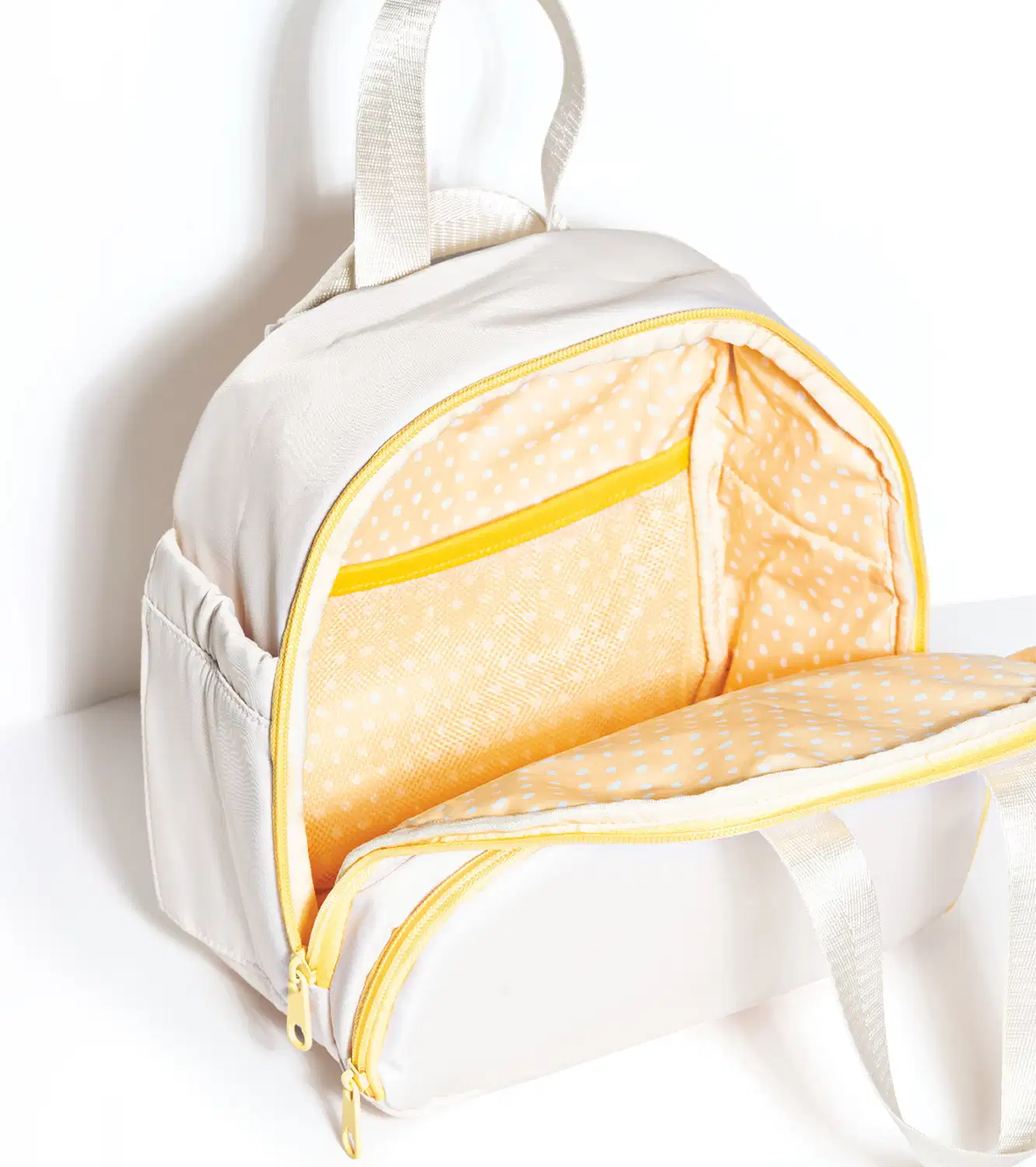 Frasqueira branca com detalhe e zíperes amarelos. Na imagem, o produto está aberto, mostrando o interior em tecido amarelo com bolinhas brancas e divisórias internas.