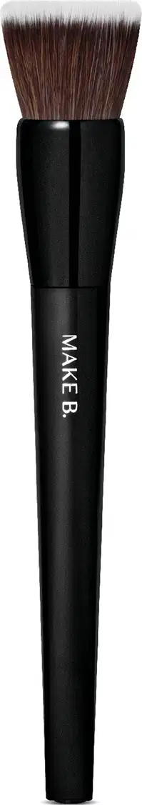 Pincel de maquiagem de formato cilíndrico e alongado. O cabo é preto e possui o texto "MAKE B." impresso. As cerdas são macias e de cor castanha escura.  O design é simples e minimalista, com o foco no desempenho e funcionalidade do produto.
