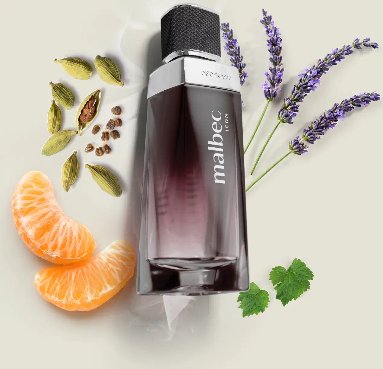 Vidro com degradê de preto e branco, detalhe prateado próximo à tampa preta e rótulo com letras cinza de desodorante colônia Malbec Icon em primeiro plano, rodeado por especiarias, flores de lavanda e fatias de laranja sobre superfície clara.