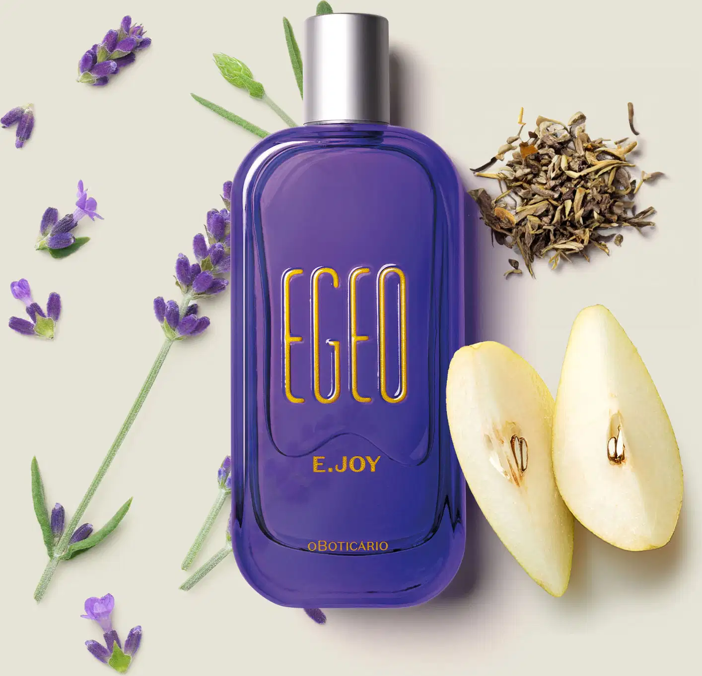 Vidro retangular azul com cantos arredondados, tampa prateada e letras na cor bege escuro de desodorante colônia Egeo E.Joy sobre superfície clara com folhas e flores de lavanda, acompanhado de fatias de maçã amarela.