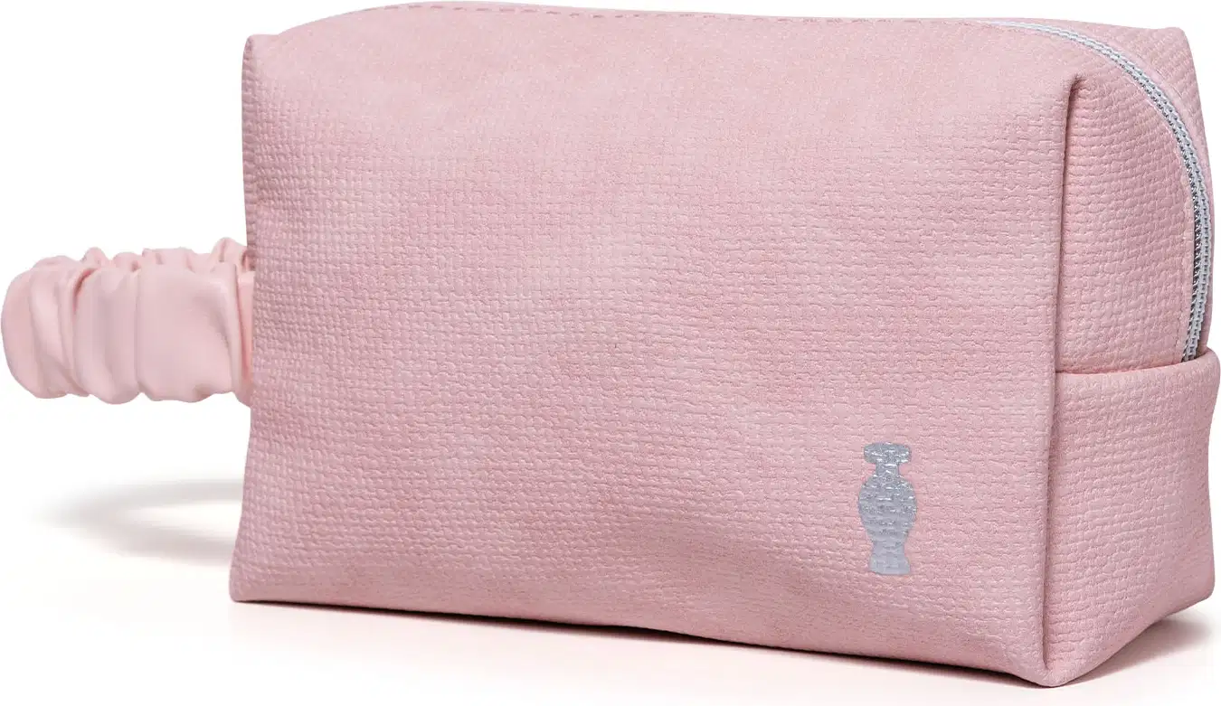 Nécessaire retangular de tecido na cor rosa com alça de transporte franzida e logo da marca O Boticário estampado.