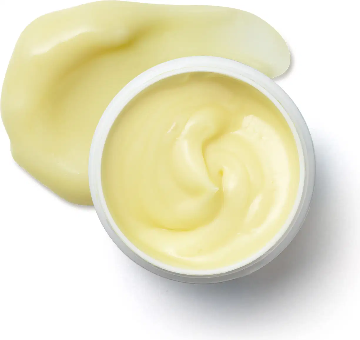 Pote branco aberto com creme amarelo dentro dele e porção de creme espalhado na superfície branca.