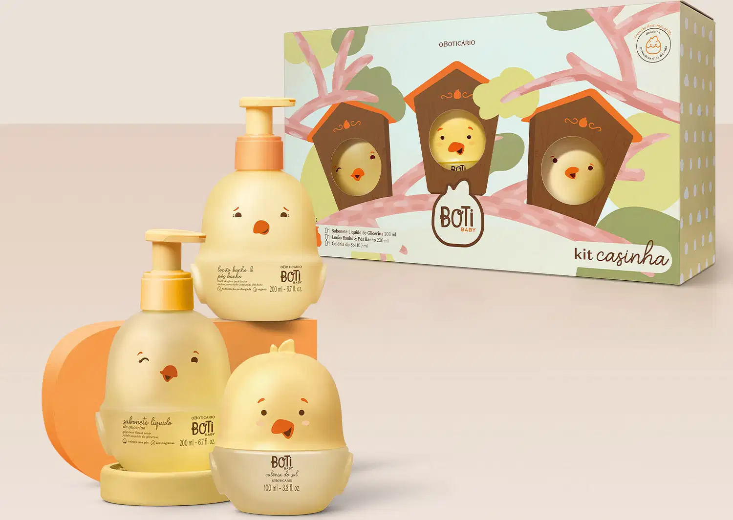 Três frascos em forma de pintinhos amarelos com detalhes laranja, sendo um de colônia do sol e outros dois com tampa dosadora laranja: um de loção banho e pós banho e o outro de sabonete líquido de glicerina. Ao lado, a caixa com ilustração de casinhas.