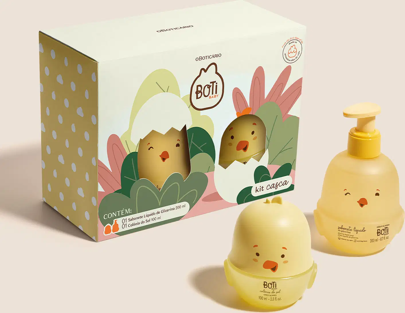 Kit Boti Baby que traz uma embalagem com desenhos de pintinhos saindo de dentro da casca do ovo em meio a folhagens.  Ao lado da embalagens, dois frascos em forma de pintinhos amarelos, sendo um de sabonete líquido de glicerina e outro de colônia do sol.