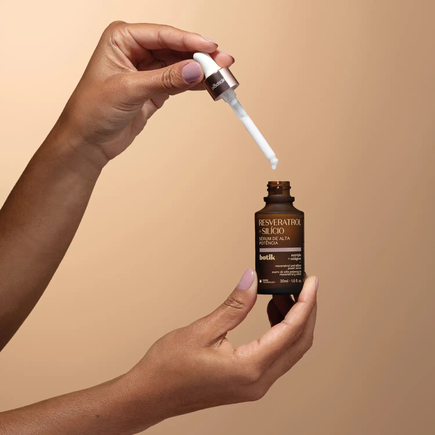 Uma mão segurando uma tampa dourada com conta-gotas branco e a outra mão segurando um frasco marrom com letras amarelas de sérum de alta potência Botik Resveratrol e Silício em fundo em tons de bege.