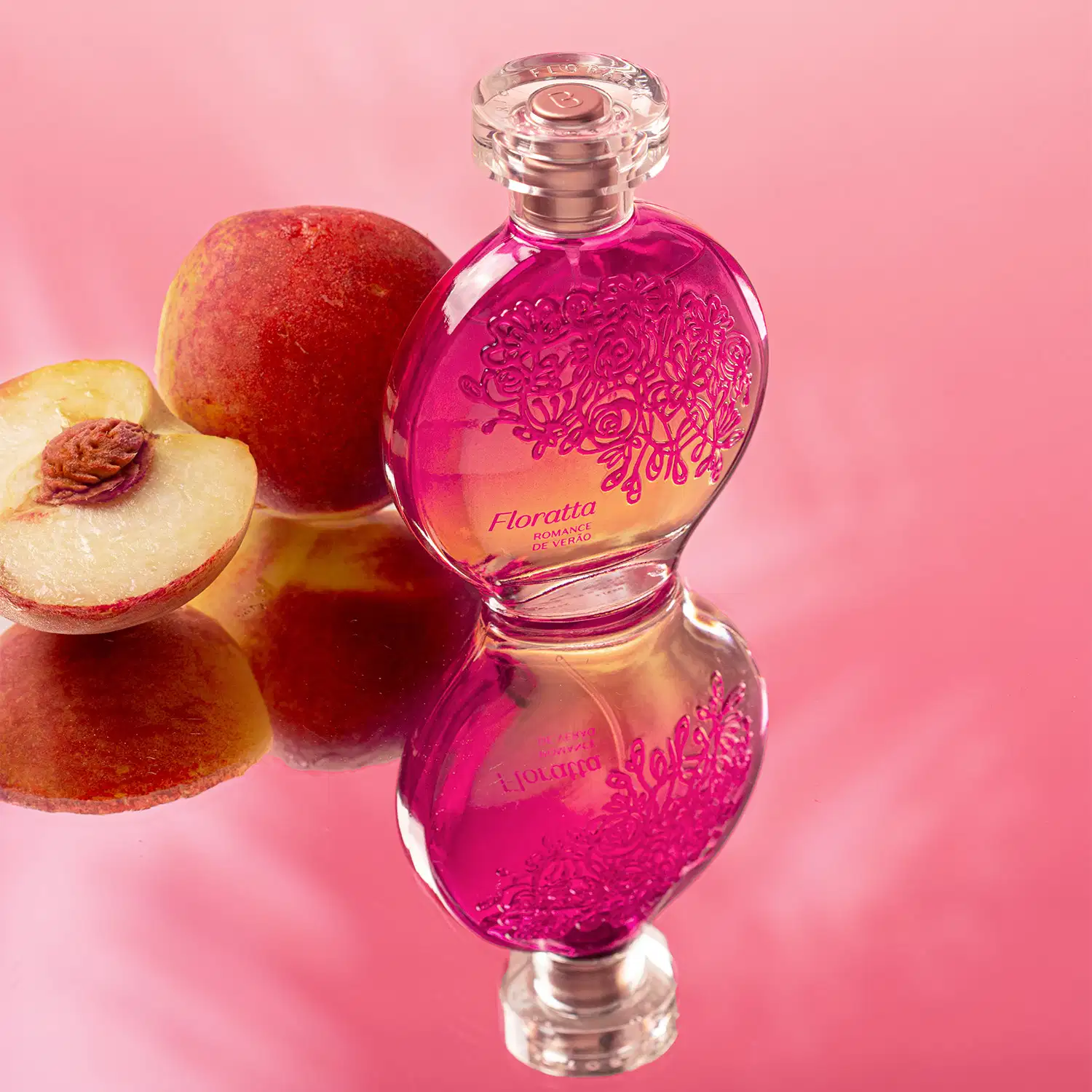 Vidro redondo com líquido rosa, floral em relevo rosa escuro, pulverizador prateado e tampa transparente contendo desodorante colônia Floratta Romance de Verão rodeado por frutas frescas em fundo rosa.