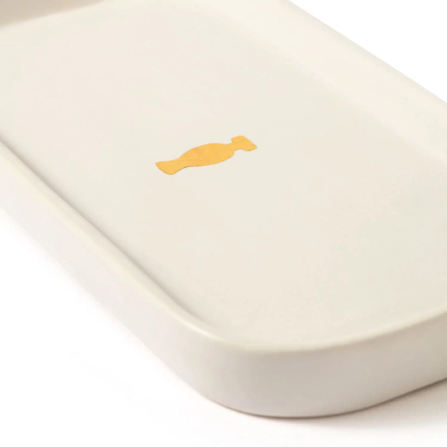 Bandeja para lavabo branca da marca Casa 214 no formato retangular com cantos arredondados e com logo do Boticário em dourado no centro.