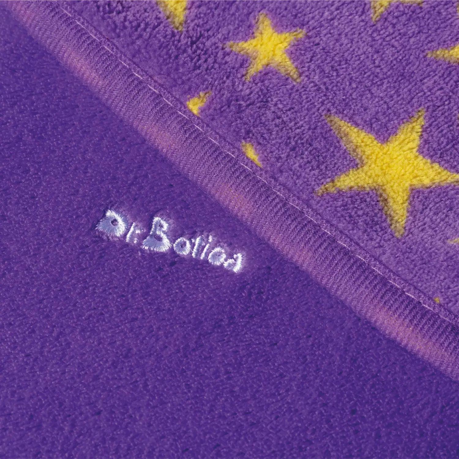 Textura roxa felpuda com estrelas amarelas, com destaque para a marca Dr. Botica bordada em branco.