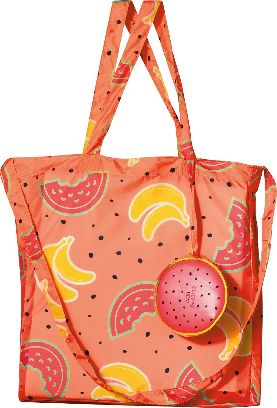 Sacola com alça de ombro e transversal na cor rosa com ilustrações de melancias, bananas e sementes pretas da marca Cuide-se Bem Feira.