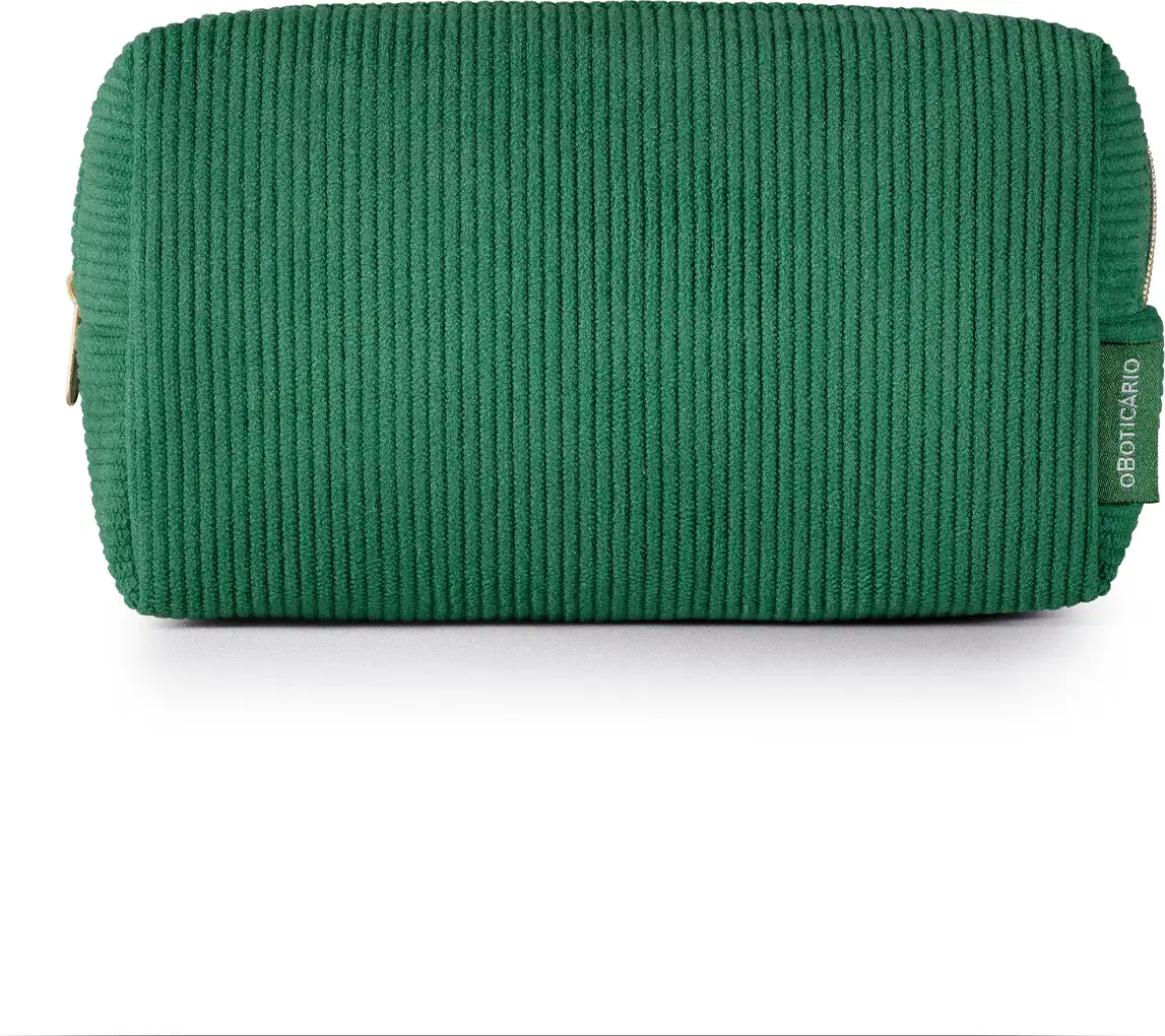 O produto apresentado é uma necessaire de cor verde escuro, com textura canelada. Possui um zíper na parte superior e uma etiqueta com o logotipo da marca O Boticário visível.