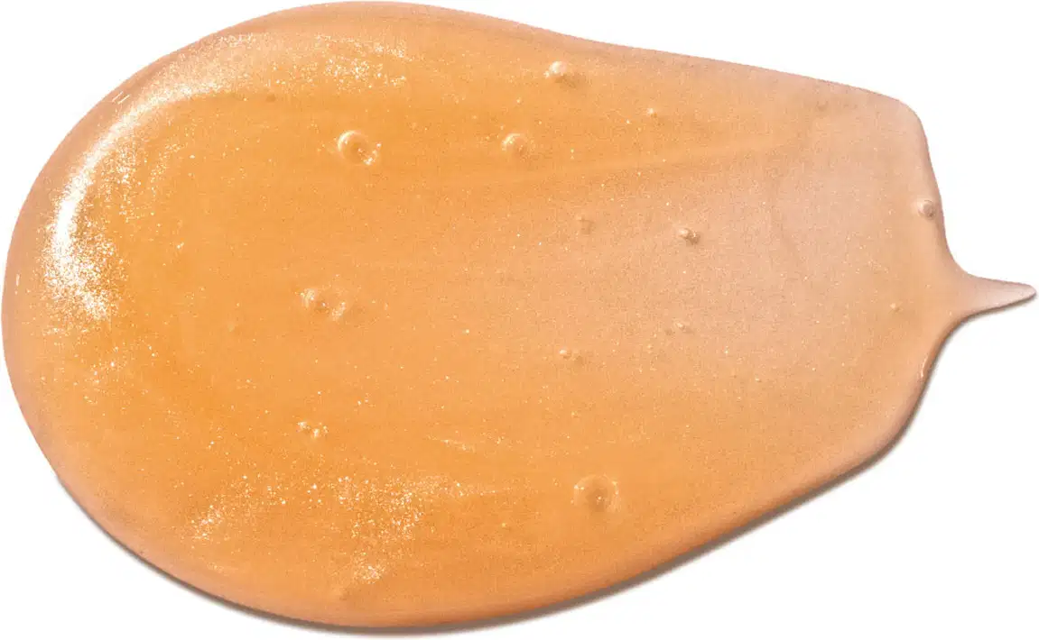 Imagem da textura gelatinosa e brilhante de tom alaranjado, com pequenas bolhas, em superfície lisa e uniforme do shampoo infantil para cabelo cachados Dr. Botica.