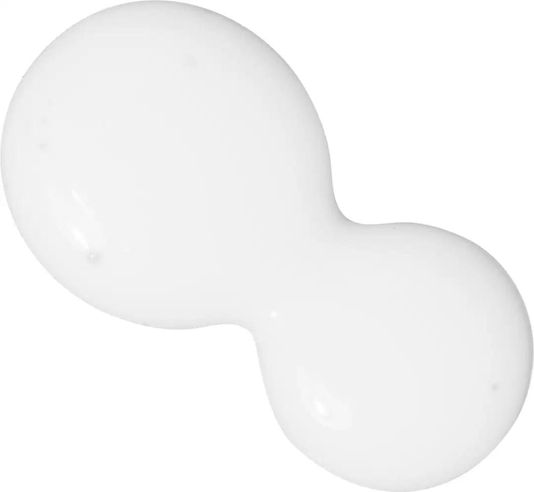 A imagem mostra algumas gotas do produto derramadas sobre uma superfície. É possível ver uma textura cremosa na cor branca, com pequenas bolhas de ar.