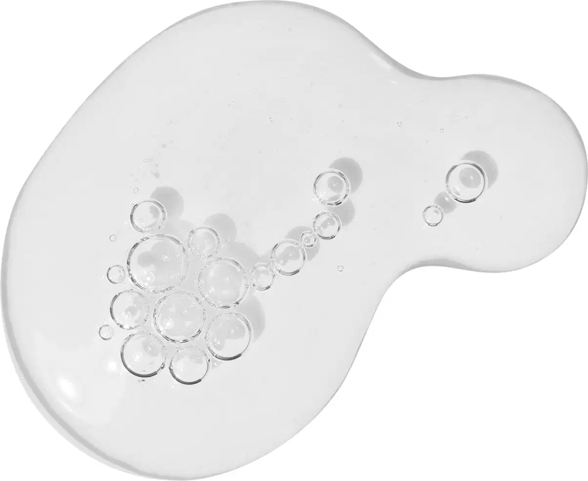 A imagem mostra algumas gotas do gel de limpeza antioleosidade Malbec Facial derramadas sobre uma superfície. É possível ver uma textura aquosa transparente, com pequenas bolhas de ar.